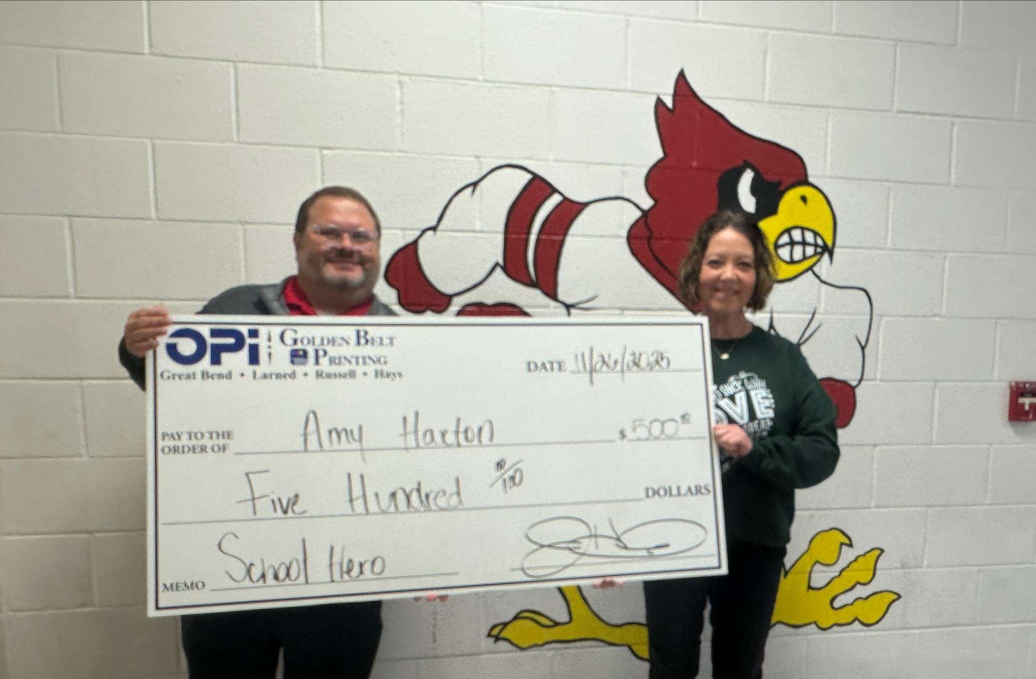 OPI's Joey Bahr presents Hoisington High School coach and teacher Amy Haxton with a $500 check after she was named the Eagle Media Nominate a School Hero winner for November.