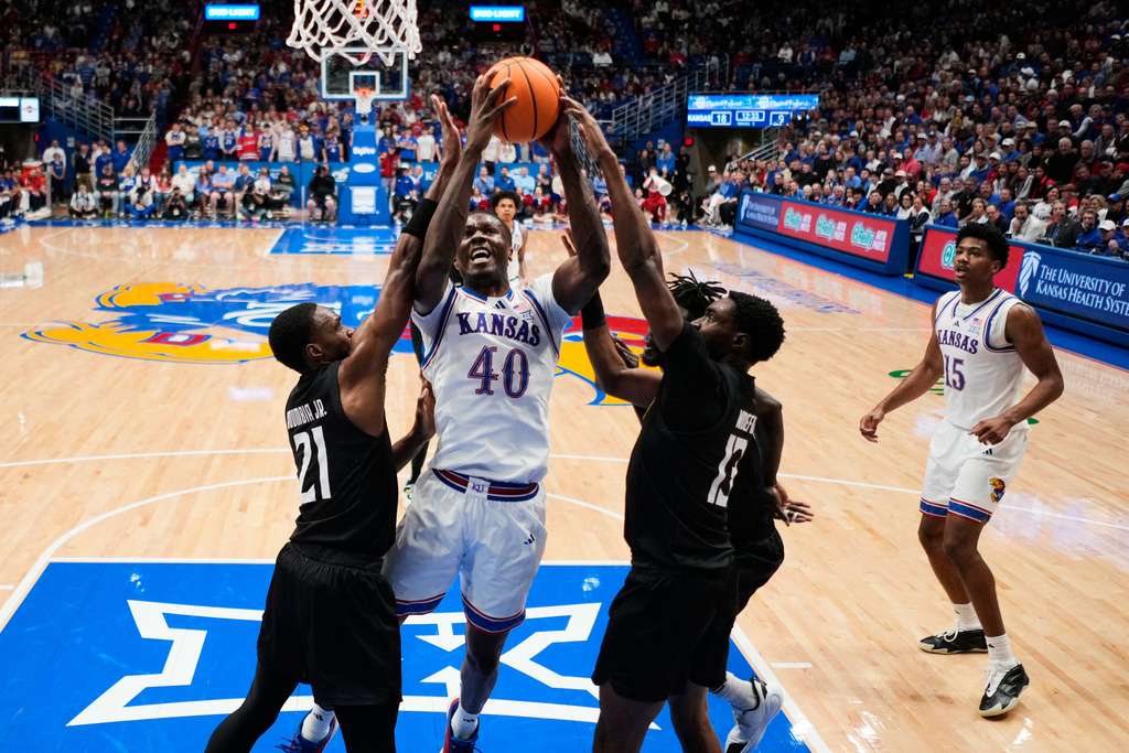 Kansas forward Flory Bidunga (40) shoots between Towson forward Jack Doumbia Jr. (21) and guard Chike Ndefo (13) during the first half of an NCAA college basketball game Tuesday, Dec. 16, 2025, in Lawrence, Kan. (AP Photo/Charlie Riedel)