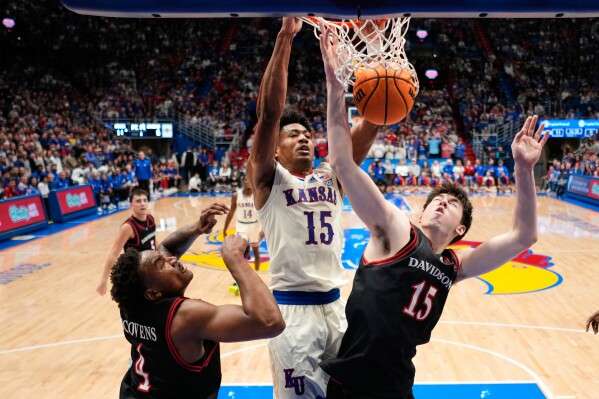 Kansas forward Bryson Tiller (15) dunks the ball over Davidson forward Sean Logan, right, during the first half of an NCAA college basketball game Monday, Dec. 22, 2025, in Lawrence, Kan. (AP Photo/Charlie Riedel)