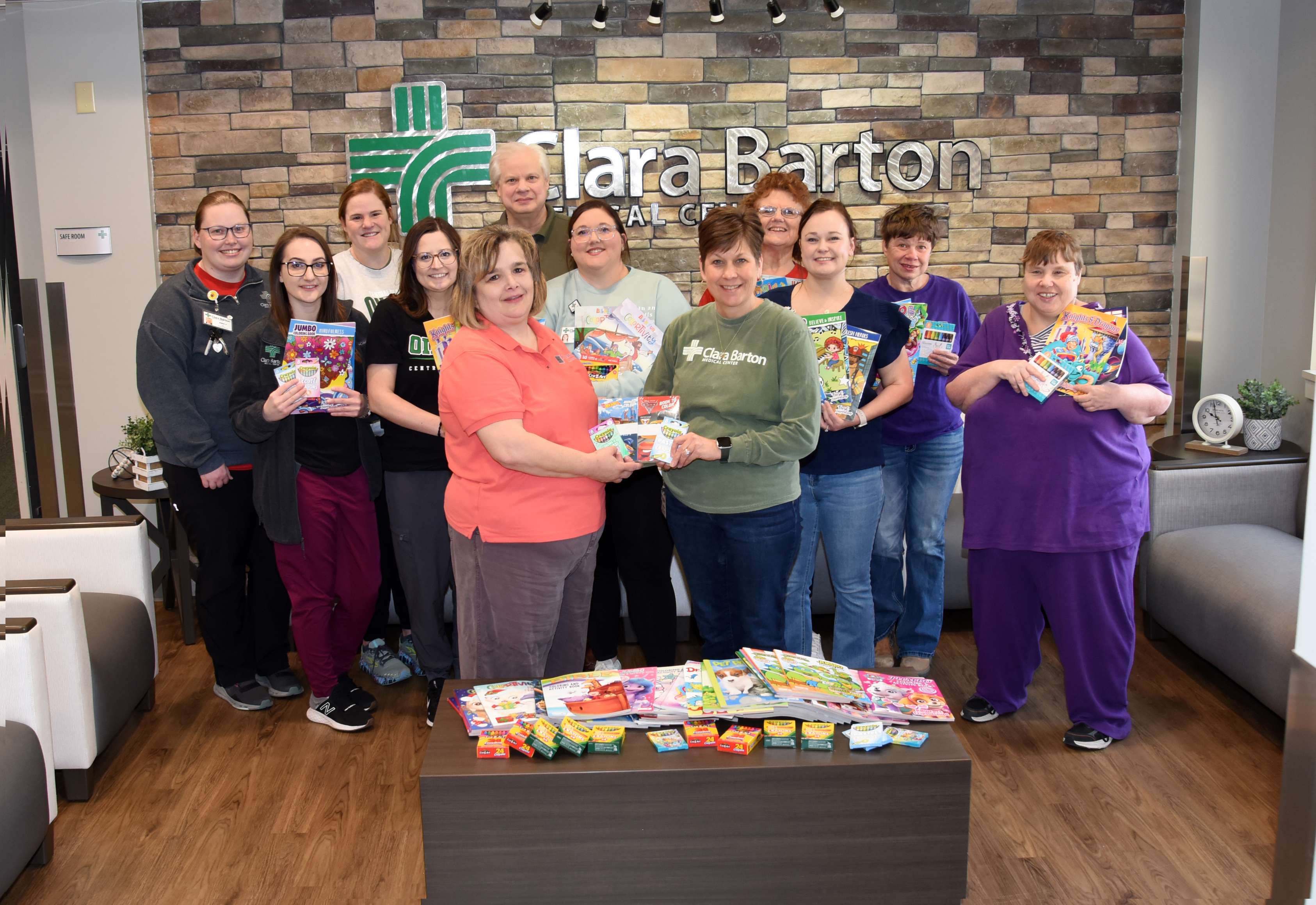 Rosewood Miracle Workers AKTION Club members and Clara Barton Hospital staff stand among the donations of coloring books and crayons recently donated to the Hoisington hospital and clinic. Left to right: Emily Johnson (CBH), Karly Esfeld (CBH), Lauren Kristek (CBH), Macy Liebl (CBH), Frankie Pelster (RW), Jay Tusten (CBH CEO), April Gatton (CBH), Michelle Moshier (CBH), Jeannie Triplett (RW), Chantel McKenzie (CBH), Robin Bethel (RW), and Beth Mattocks (RW).