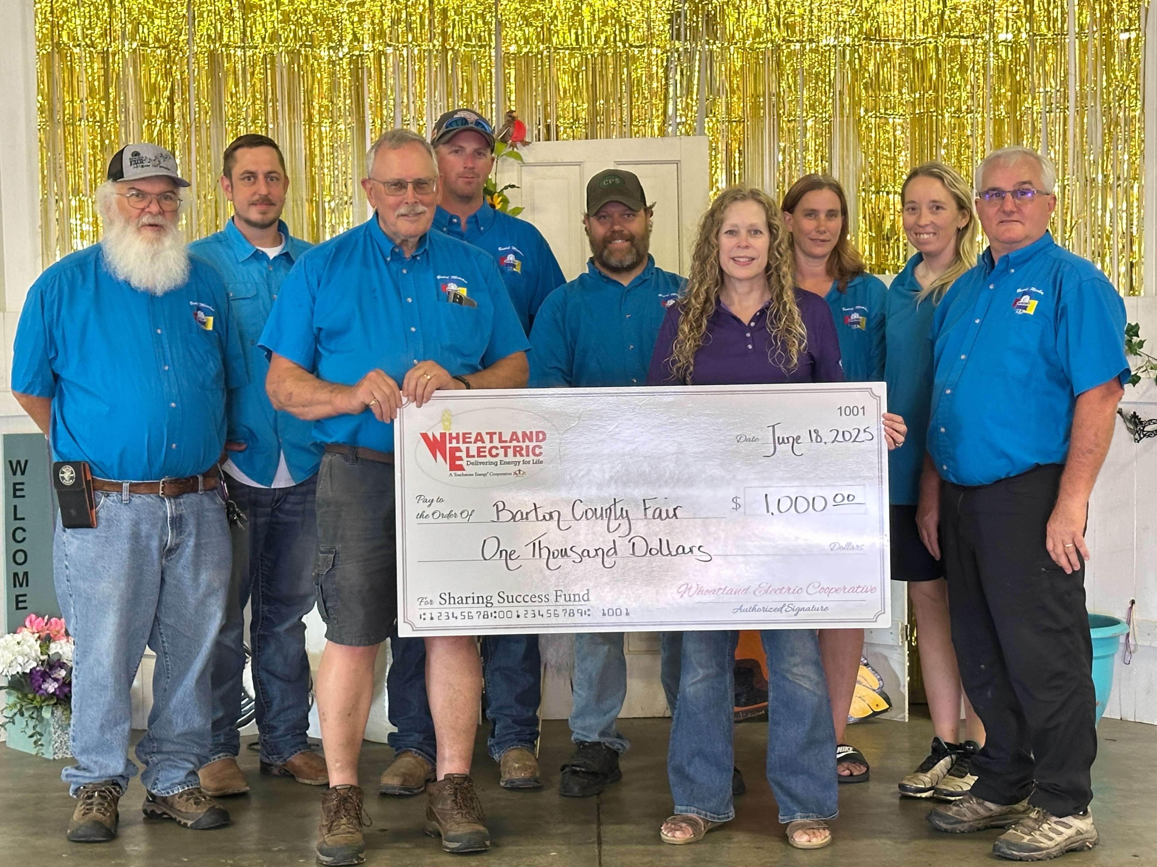 Wheatland Electric Cooperative’s Member Services and Key Accounts Manager Mary Hoisington, (fourth from right) presents a Sharing Success grant to the Barton County Fair. The grant will be used to help replace a worn-out refrigerator in the food stand.