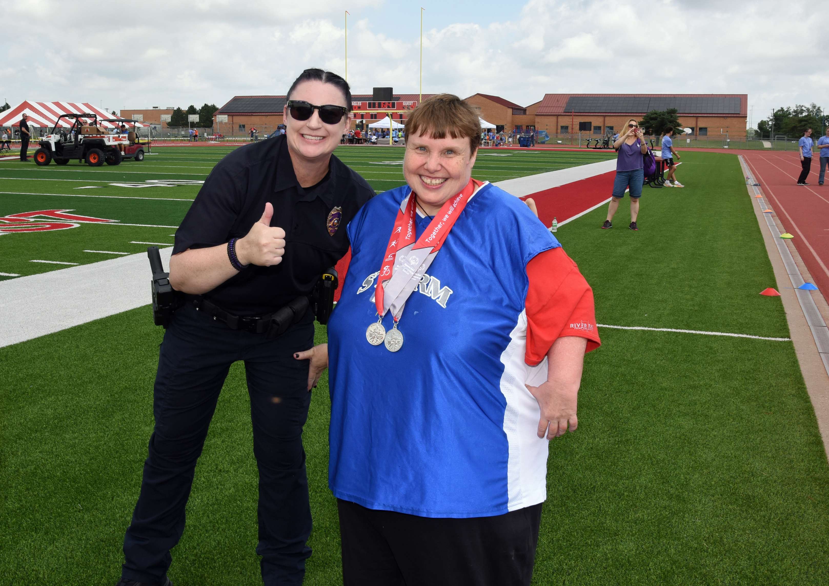 Storm Athlete Beth Mattocks celebrates her racing accomplishment with a Wichita Police Officer at the Special Olympics Kansas Summer Games at Maize High School on June 7.