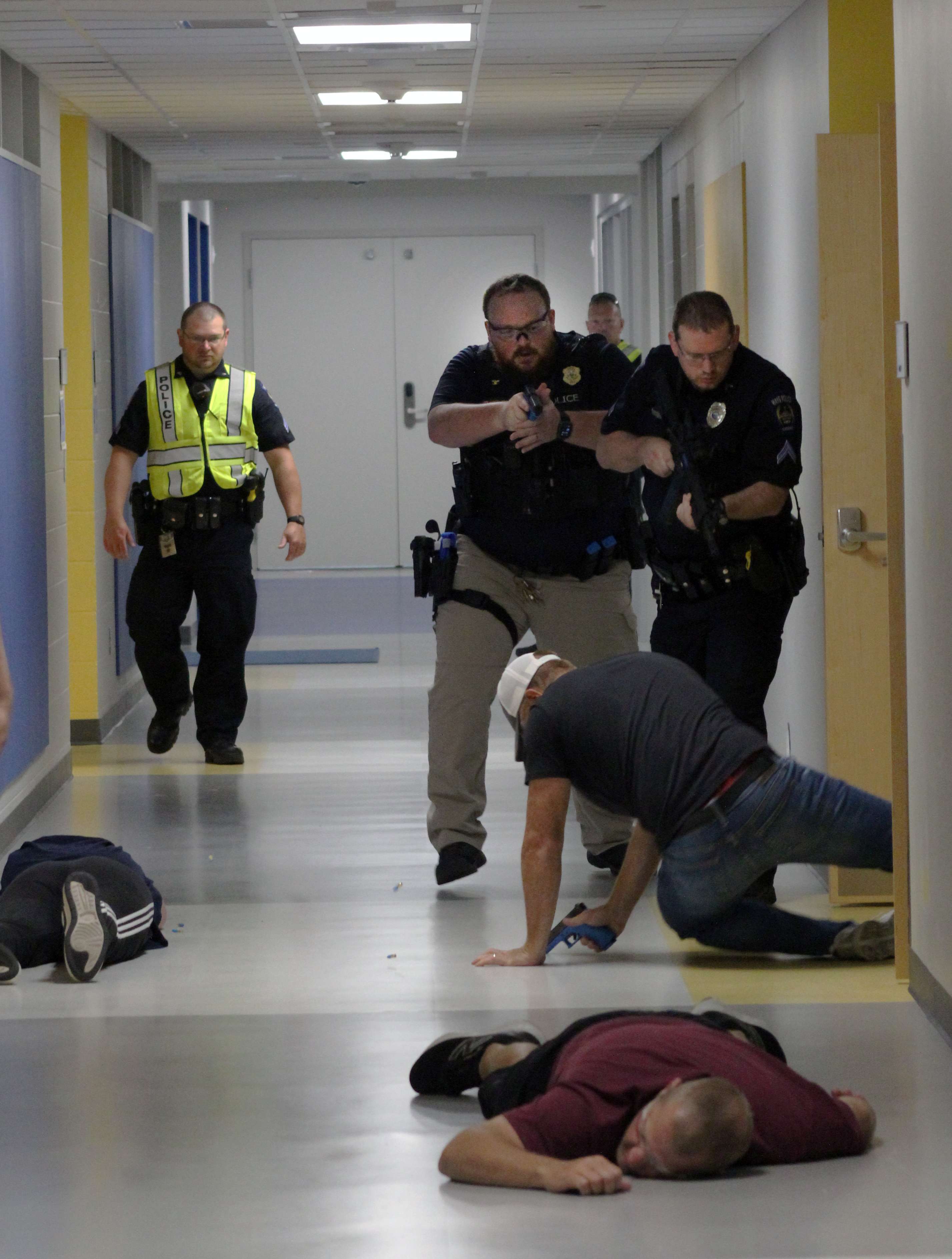 Officers subdue an active shooter during a training exercise&nbsp;on Wednesday at Roosevelt Elementary School as actors portray victims lying in a hallway. A training officer in a yellow vest at left observes. Photo by Cristina Janney/Hays Post