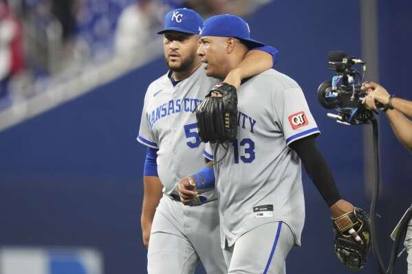 Kansas City Royals relief pitcher Carlos Estevez, left, and first baseman Salvador Perez (13) walk from the field after defeating the Miami Marlins in a baseball game, Sunday, July 20, 2025, in Miami. (AP Photo/Lynne Sladky)