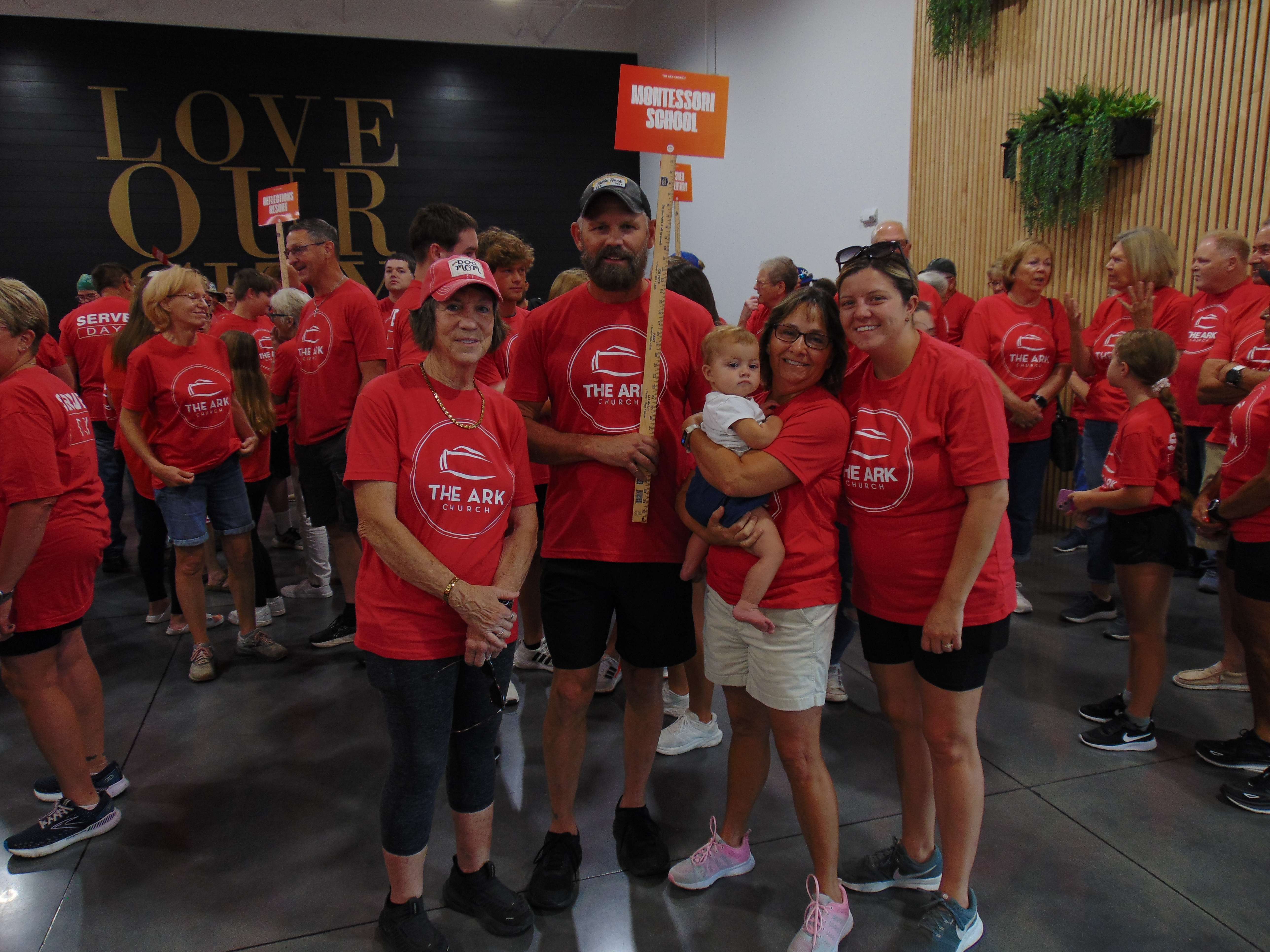 Group of volunteers holding up "Montessori School" sign before the service work began on Saturday, July 19; photo by Nicolas Fierro