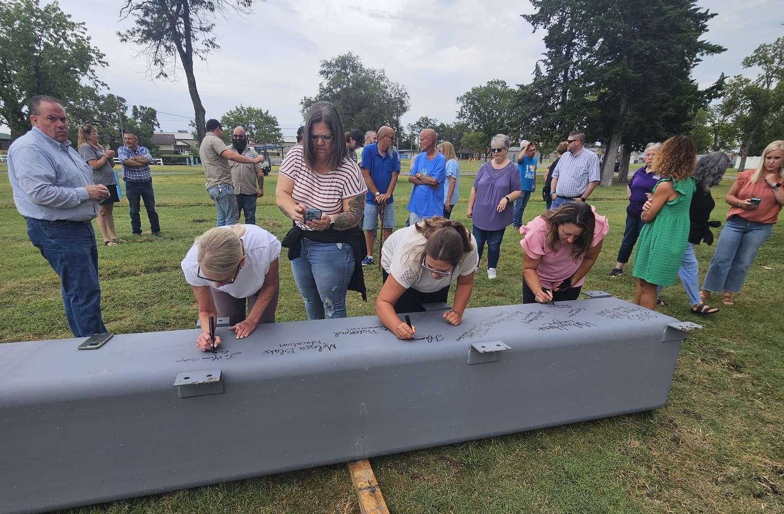 Bryan Schulz, Kansas State Fair General Manager (far left), watches Kansas State Fair sign a steel support beam for the Peoples Bank and Trust Arena Canopy. (Photo courtesy Kansas State Fair) 