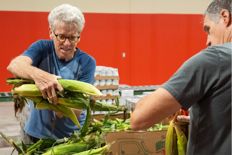 Steve Vossler, left, volunteers at the Harvesters distribution center in Lawrence, Kansas.&nbsp;Photo by Zane Irwin/Kansas News Service