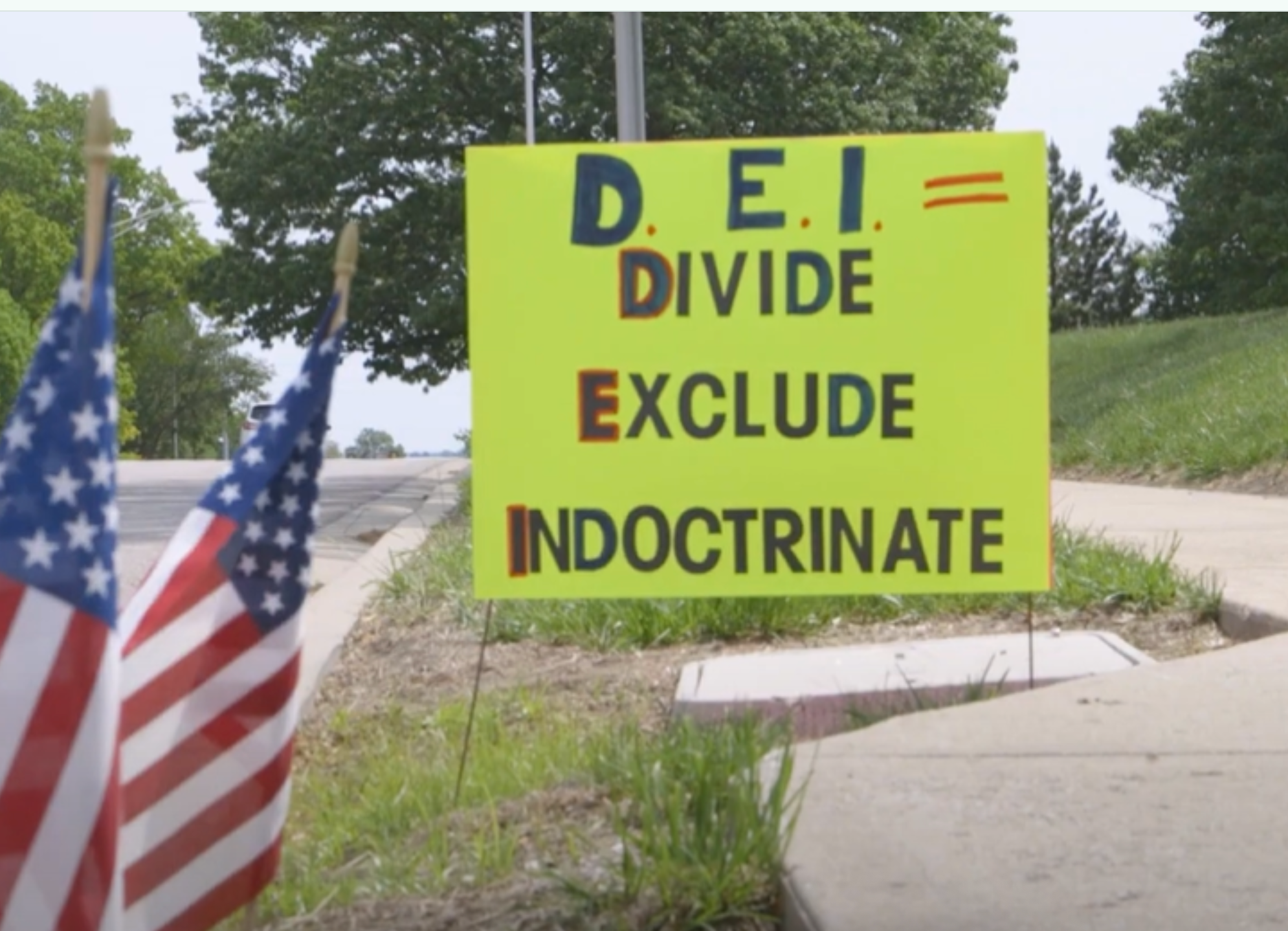At a May 10 protest in Shawnee of school district practices, anti-DEI signs line the curb. (Kansas Reflector screen capture from Darrin Dressler video)