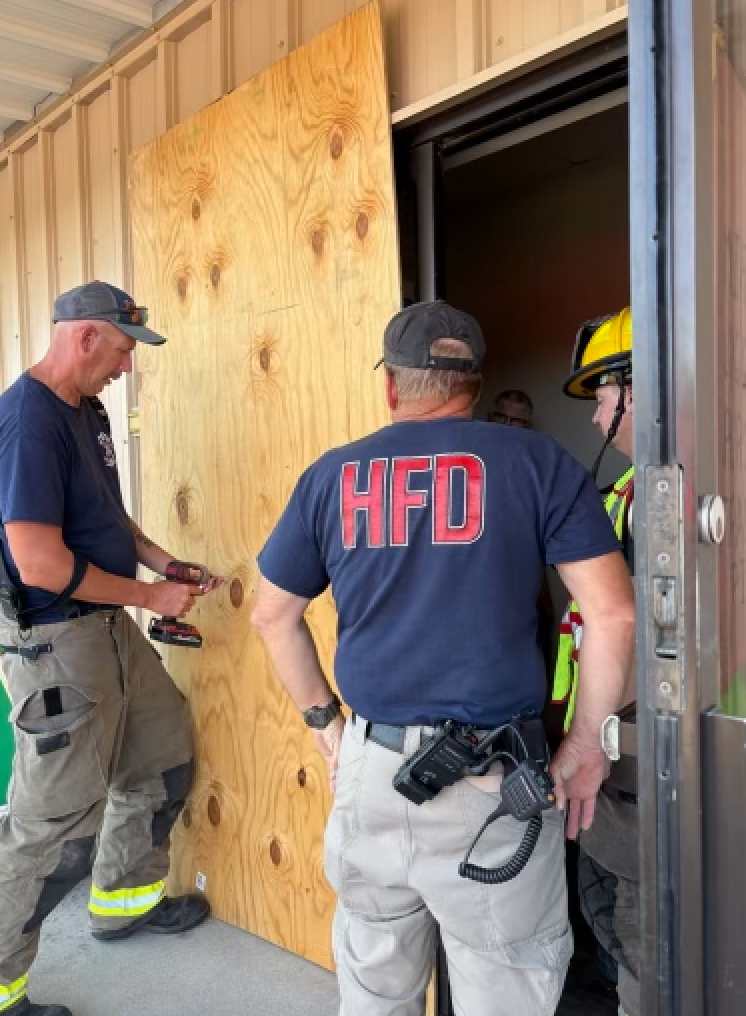 Hays firefighters place a piece of plywood on the broken glass door of the Habitat for Humanity of Ellis County building in Hays. Courtesy photo