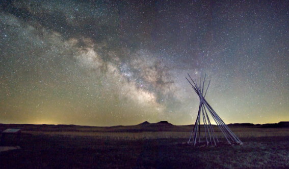 NPS Photo: The Fossil Hills silhouetted against the Milky Way with tipi poles in the foreground.