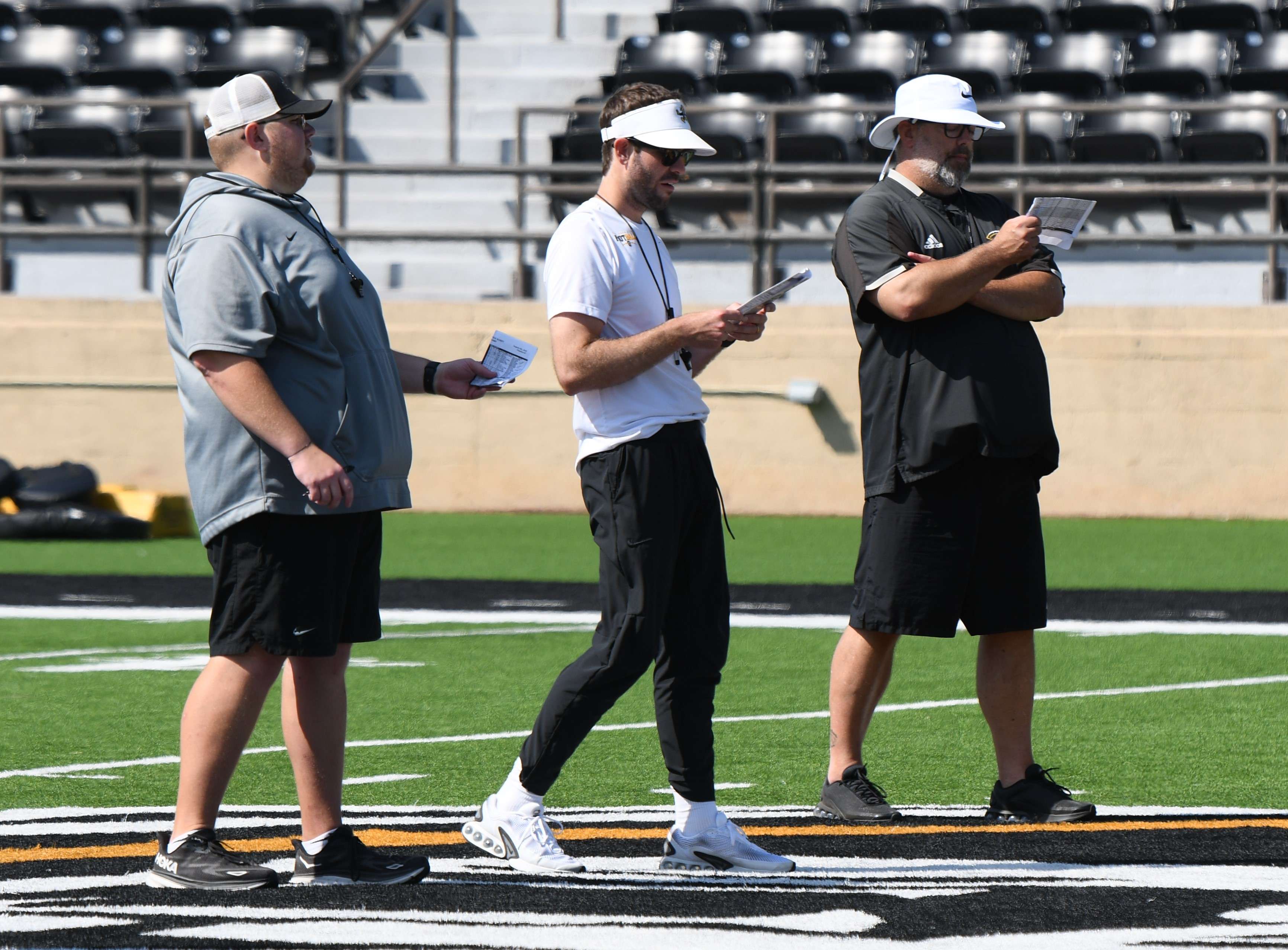 Fort Hays State coaches Kyle Murphy (left), Tom Ross (center) and Cooper Harris (right) watch on at a FHSU football practice (FHSU Athletics photo/Ryan Prickett)