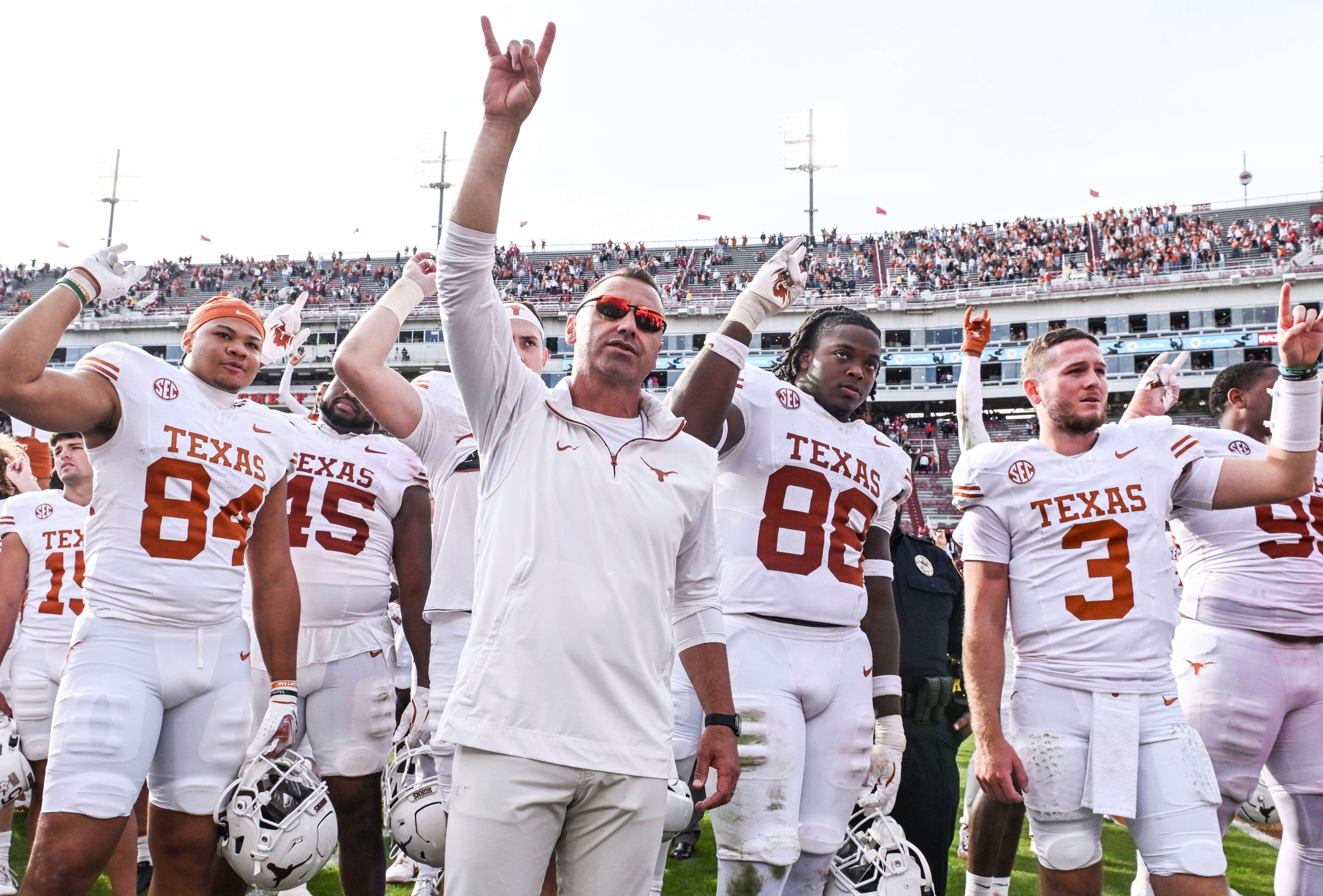 FILE - Texas tight end Jordan Washington (84), coach Steve Sarkisian, defensive back Barryn Sorrell (88) and quarterback Quinn Ewers (3) celebrate with their team after defeating Arkansas in an NCAA college football game Saturday, Nov. 16, 2024, in Fayetteville, Ark. (AP Photo/Michael Woods, File)