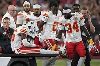 Kansas City Chiefs safety Deon Bush (26) is carted off the field after an injury against the Arizona Cardinals during the first half of an NFL preseason football game, Saturday, Aug. 9, 2025, in Glendale. (AP Photo/Doug Benc)