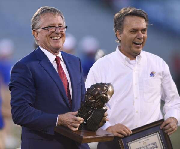  David Booth, left, receives a proclamation from then-Kansas Gov. Jeff Colyer, M.D., during halftime of a Kansas NCAA college football game in Lawrence, Kan., Sept. 1, 2018. (AP Photo/Reed Hoffmann, file)