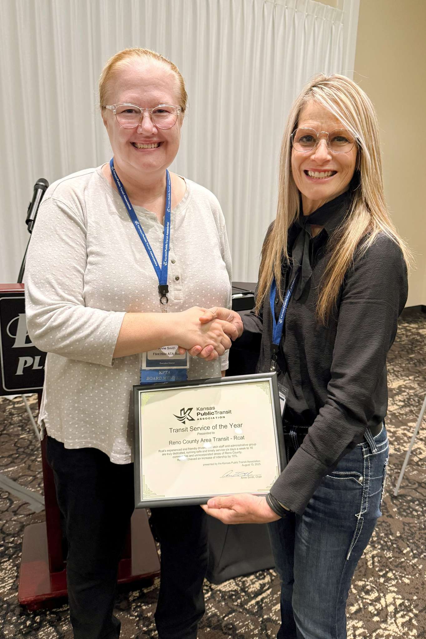 KPTA Chair Anne Smith (with ATA Bus), left, presents Natalie Goertzen, Assistant Director of the Reno County Department of Aging and Public Transportation, with the award. (Courtesy Reno County)
