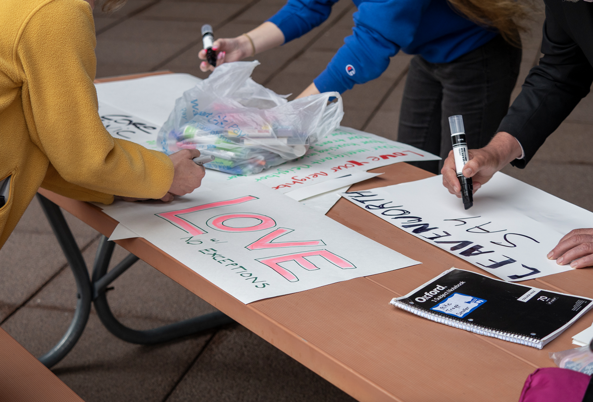 Kansas Interfaith Action members prepare signs for a May 20, 2025, demonstration outside the federal courthouse in Topeka, where they protested CoreCivic and the for-profit detention of immigrants. (Sherman Smith/Kansas Reflector)