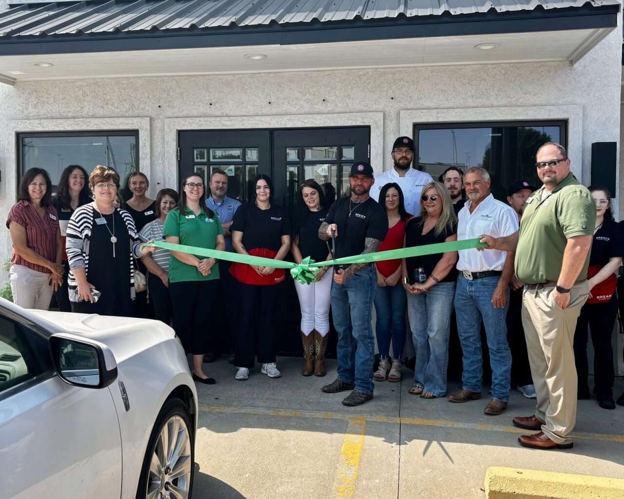 Brent Lang, Breaks Eatery & Bar owner, preparing to cut a ribbon to celebrate the restaurant's grand reopening in Hays while surrounded by family, staff and community members. Photo by Tony Guerrero/Hays Post