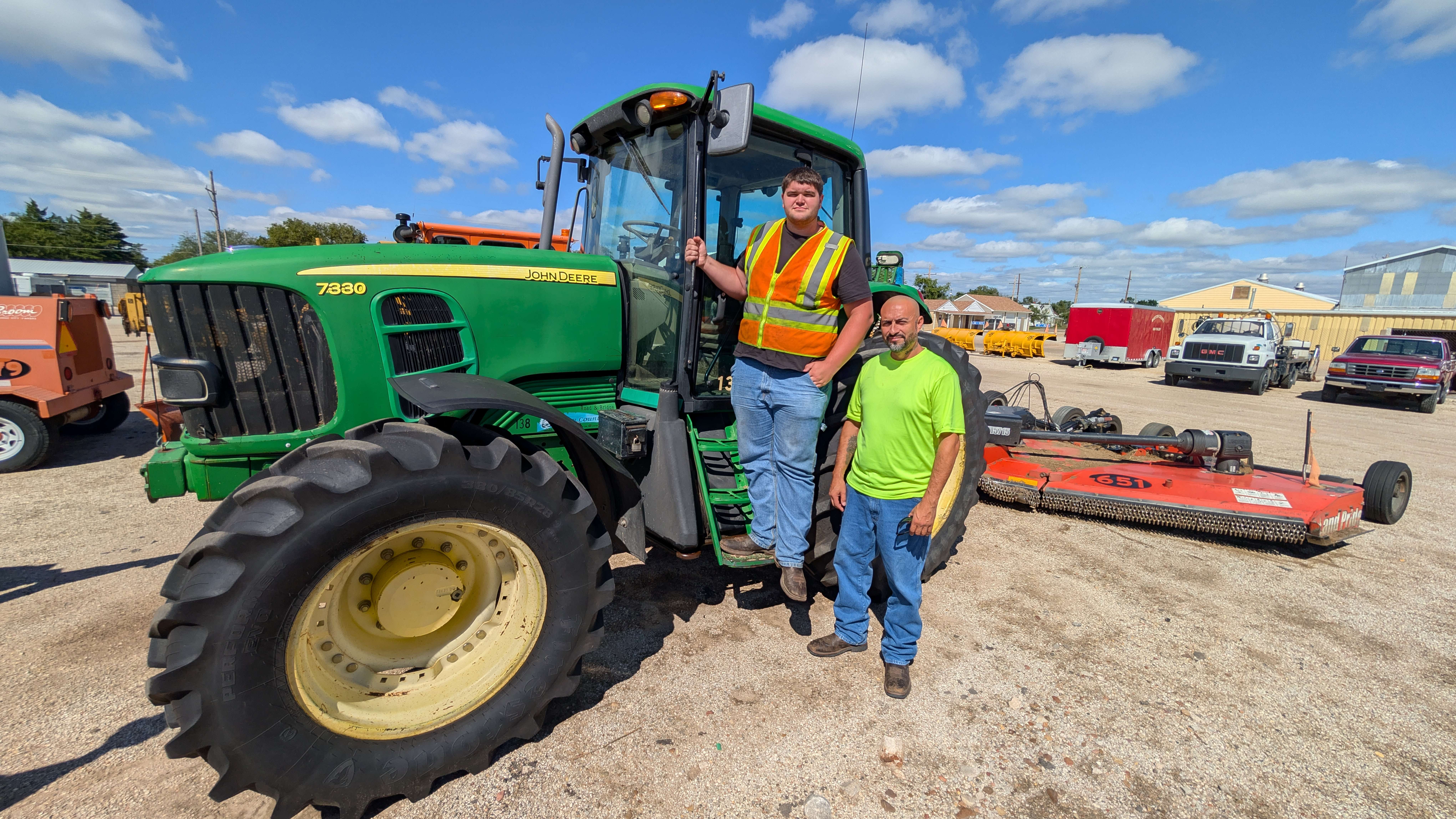 Barton County Road and Bridge Department employees Art Ramirez and Noah Deines pose by one of the mowers used to mow the 780 miles of ditches that line county blacktop roads. The two had just spent the day out cutting.