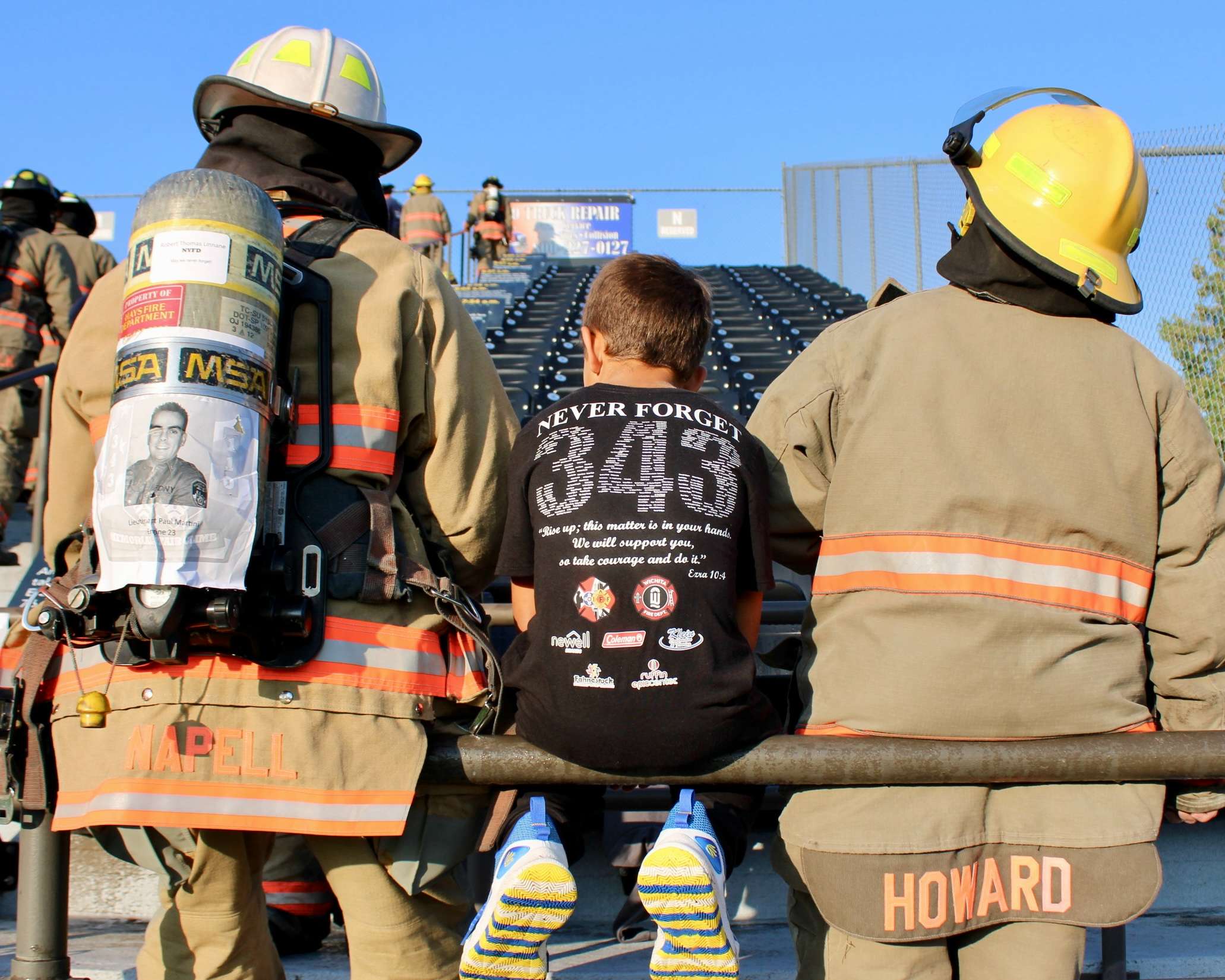 Firefighters sitting next to a boy at the 9/11 Memorial Stair Climb. Photo by Tony Guerrero/Hays Post