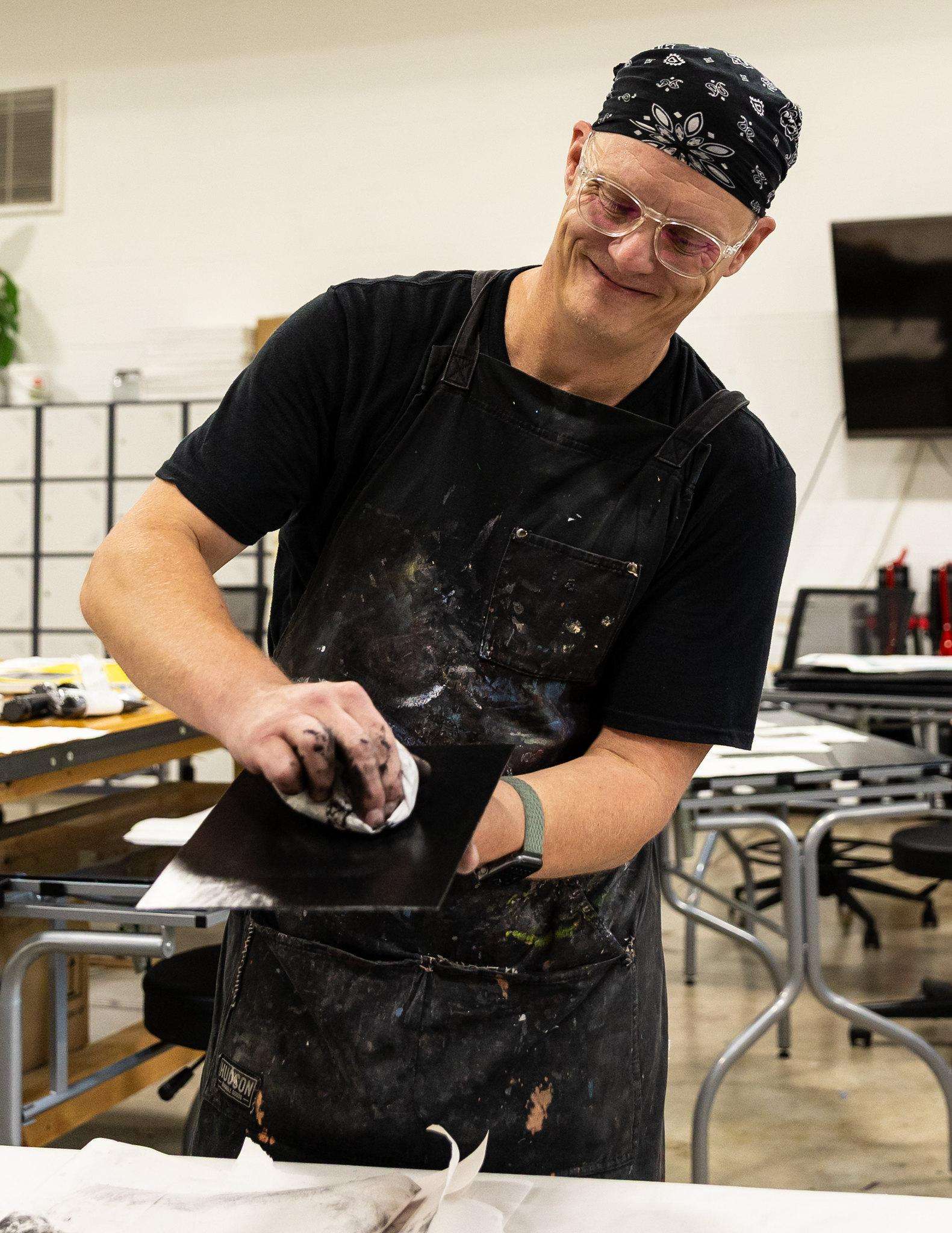 Brian Hutchinson works on restoring a printing plate of Orlin C. Baker in the art studio on the Barton Campus.
