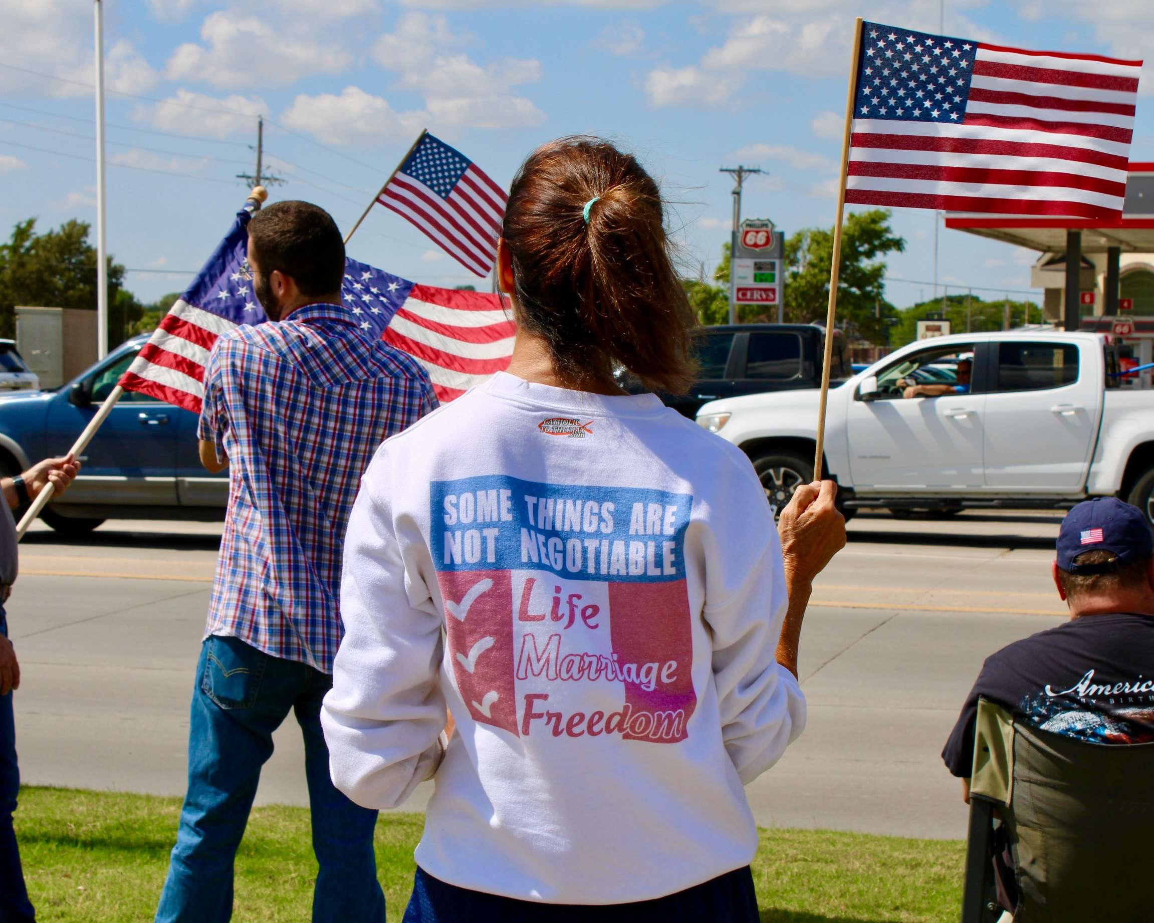 An attendee with an American flag on the corner of 27th and Vine in Hays. Photo by Tony Guerrero/Hays Post