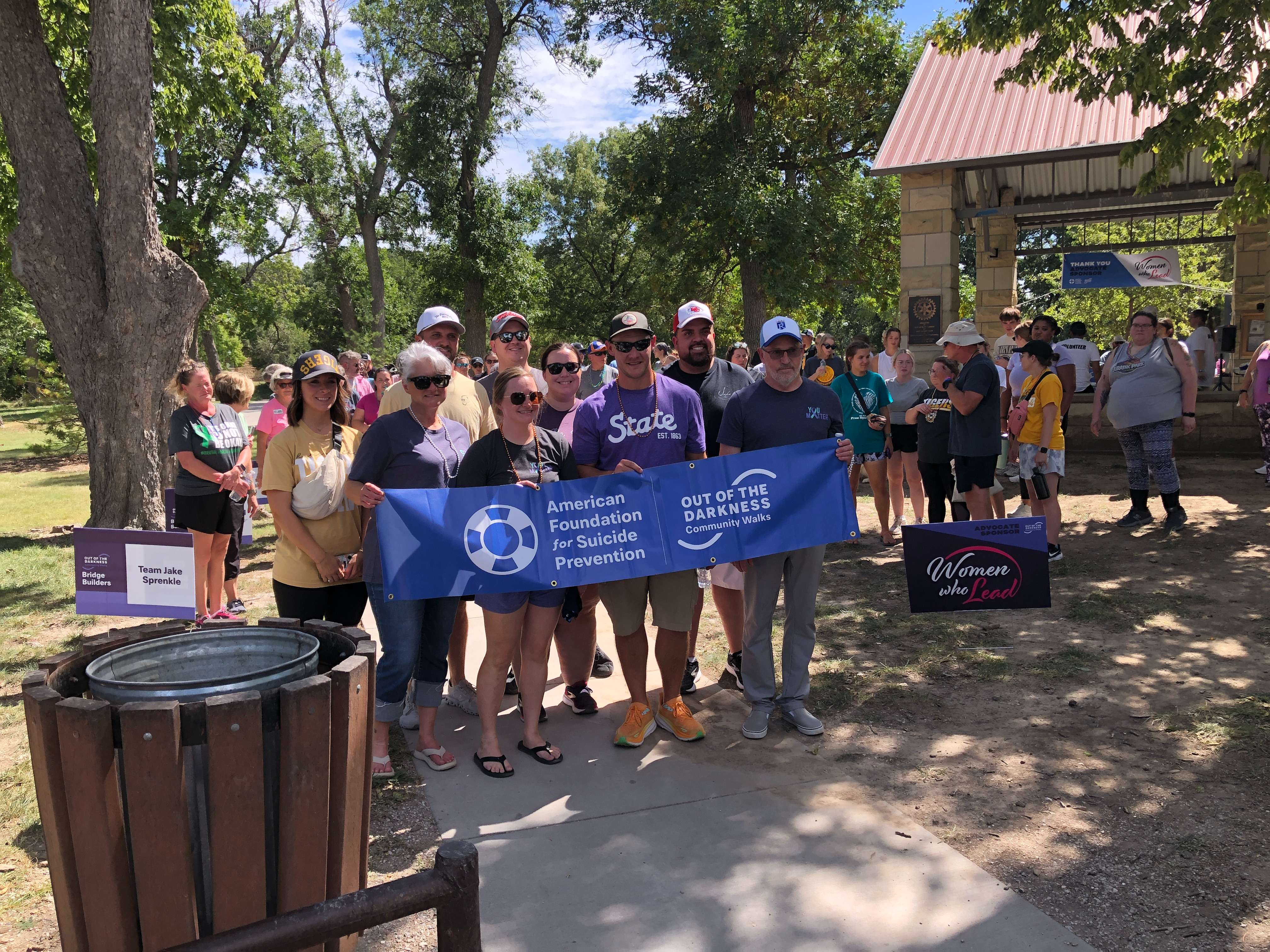 A team of walkers holds the American Foundation for Suicide Banner Saturday at the Out of Darkness Walk at Frontier Bark East in Hays. Photo by Cristina Janney/Hays Post