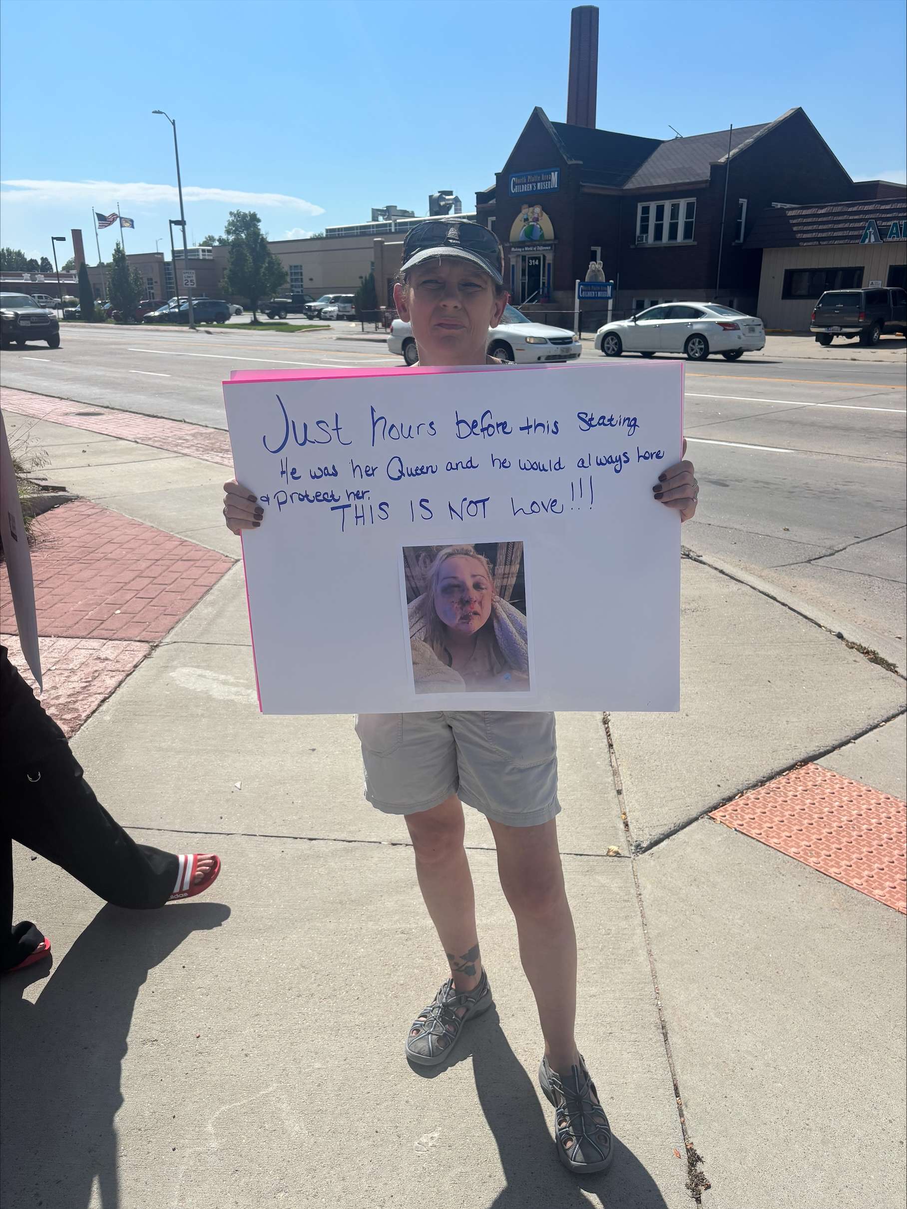 Kerri Tucker, organizer of Tuesday's protest at the courthouse, holds her sign "Just hours before this stating 'She was his queen and he would always love and protect her. THIS IS NOT LOVE'."