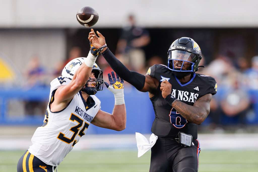 Kansas quarterback Jalon Daniels (6)passes the ball as he is pressured by West Virginia linebacker Reid Carrico (35) during the first half of an NCAA collage football game on Saturday, Sept. 20, 2025, in Lawrence, Kan. (AP Photo/Colin E. Braley)