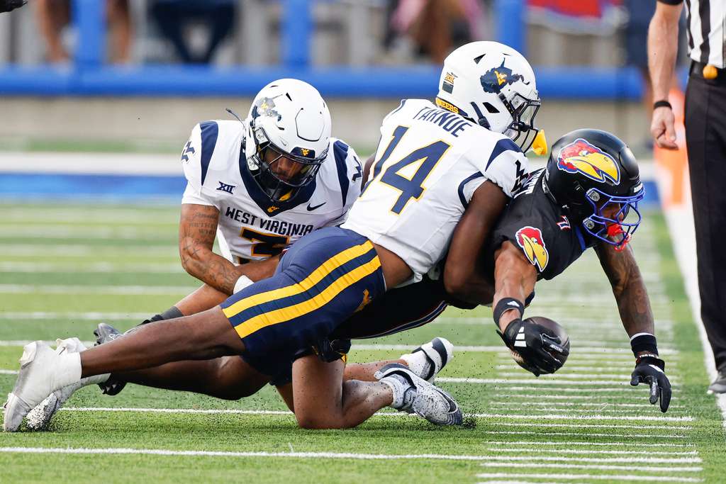 Kansas wide receiver Cam Pickett (7) catches a pass for a first down as he brought down by West Virginia cornerback Michael Coats Jr. (3) and safety Kekoura Tarnue (14) during the first half of an NCAA collage football game on Saturday, Sept. 20, 2025, in Lawrence, Kan. (AP Photo/Colin E. Braley)