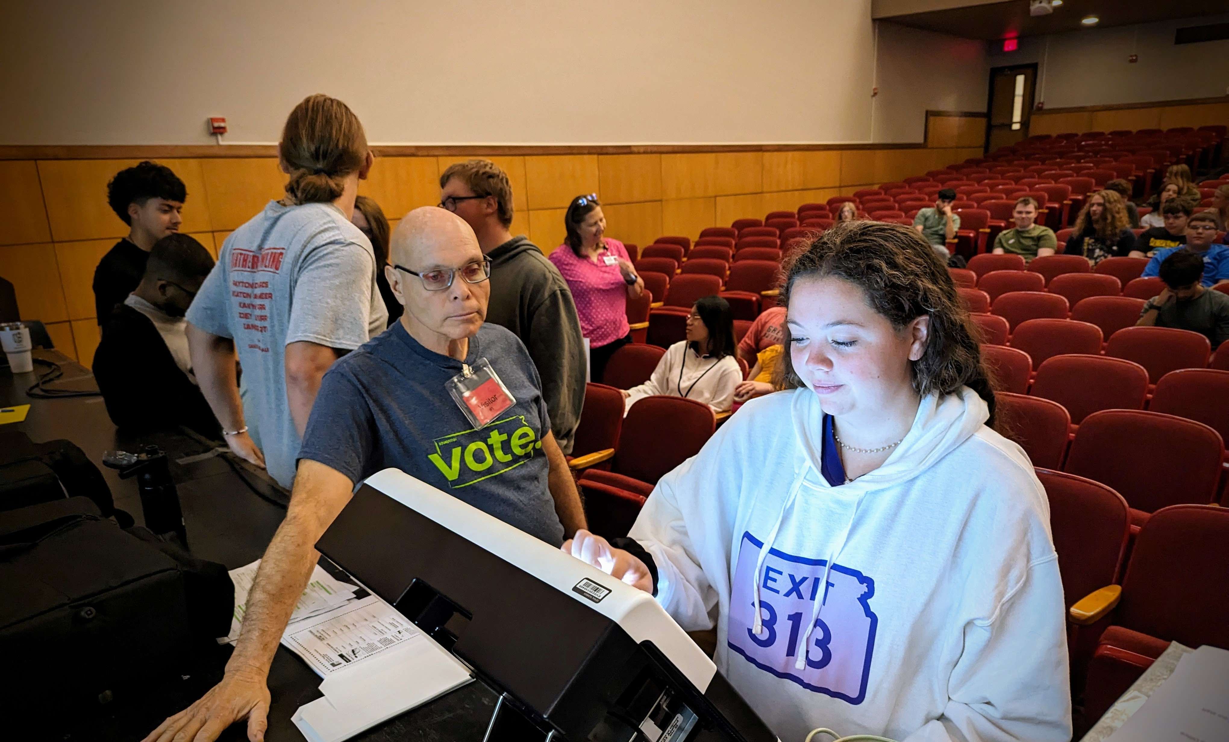 Chris Saenz, electronic equipment technician with the Barton County Clerk's Office, guides GBHS student Sheridan Johnson during last week's mock election at the school.