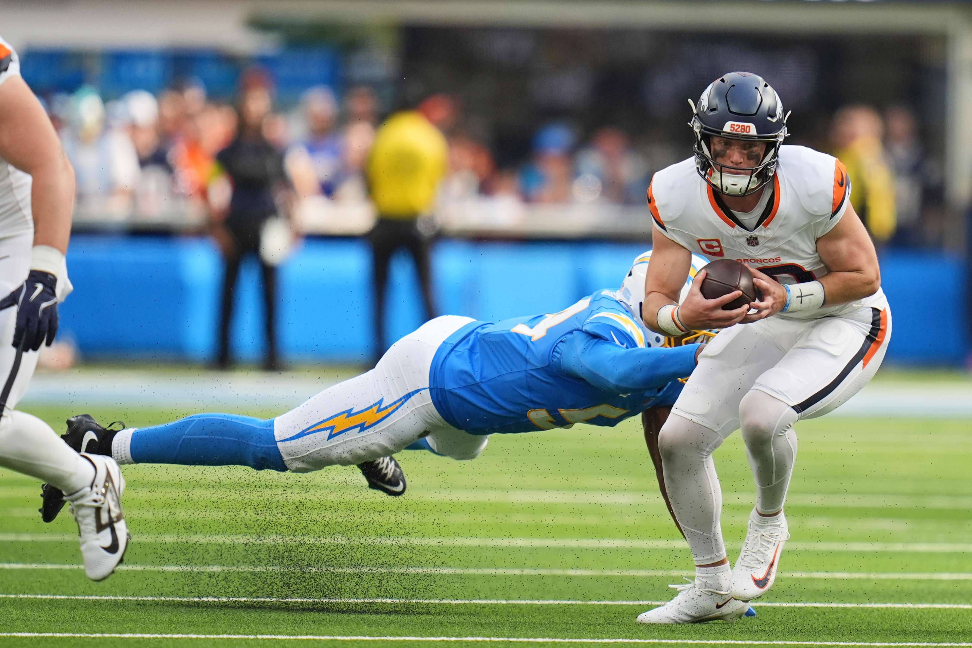 Denver Broncos quarterback Bo Nix (10) evades the tackle from Los Angeles Chargers linebacker Kyle Kennard (54) during the second half of an NFL football game Sunday, Sept. 21, 2025, in Inglewood, Calif. (AP Photo/Gregory Bull)