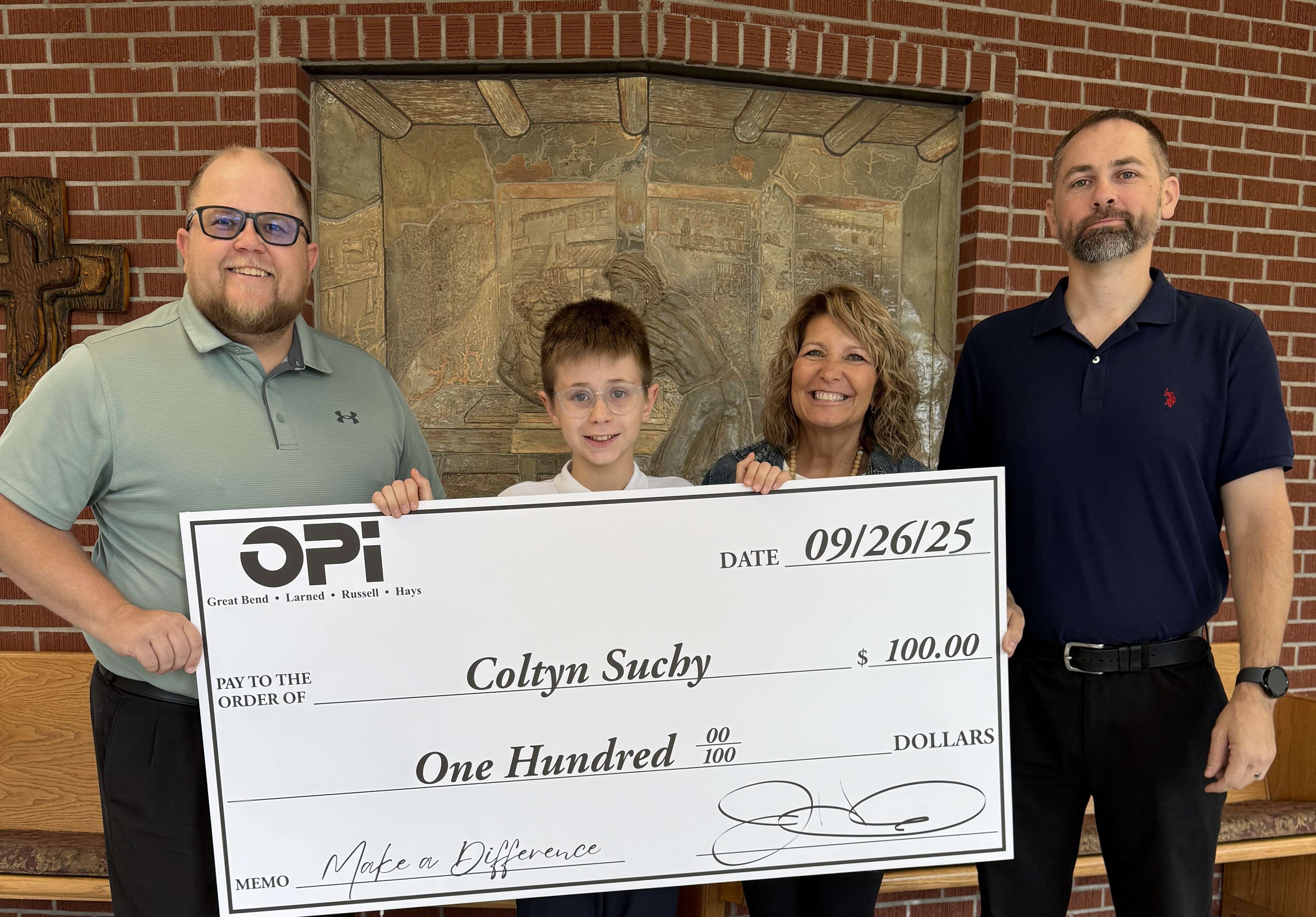 Eagle Media General Manager Dakota Tucker and OPI's Daniel Crowe present Holy Family fifth grader Coltyn Suchy with a $100 check as part of the Make a Difference Contest. Suchy and his teacher, Joan Henning, are now finalists for additional monthly contest prizes.