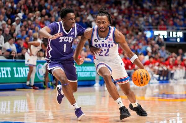 Kansas guard Darryn Peterson (22) drives past TCU guard Jayden Pierre (1) during the first half of an NCAA college basketball game Tuesday, Jan. 6, 2026, in Lawrence, Kan. (AP Photo/Charlie Riedel)