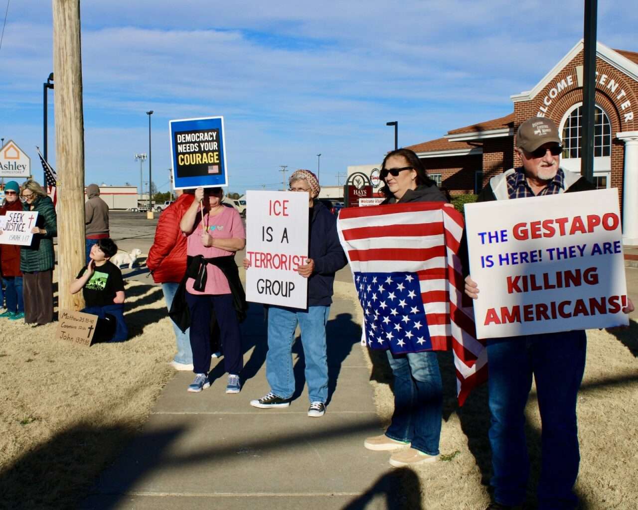 Protesters with signs Sunday on the corner of 27th and Vine streets in Hays. Photo by Tony Guerrero/Hays Post