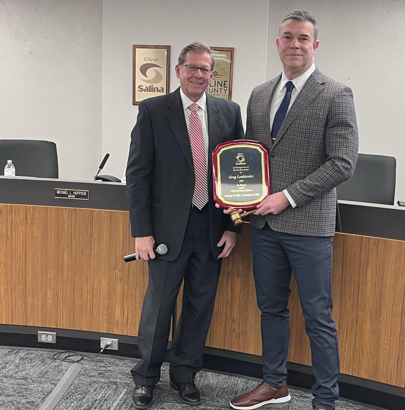 Mayor, Mike Hoppock hands Commissioner, Greg Lenkiewicz a plaque honoring his 2025 Mayoral term. Photo by Nicolas Fierro