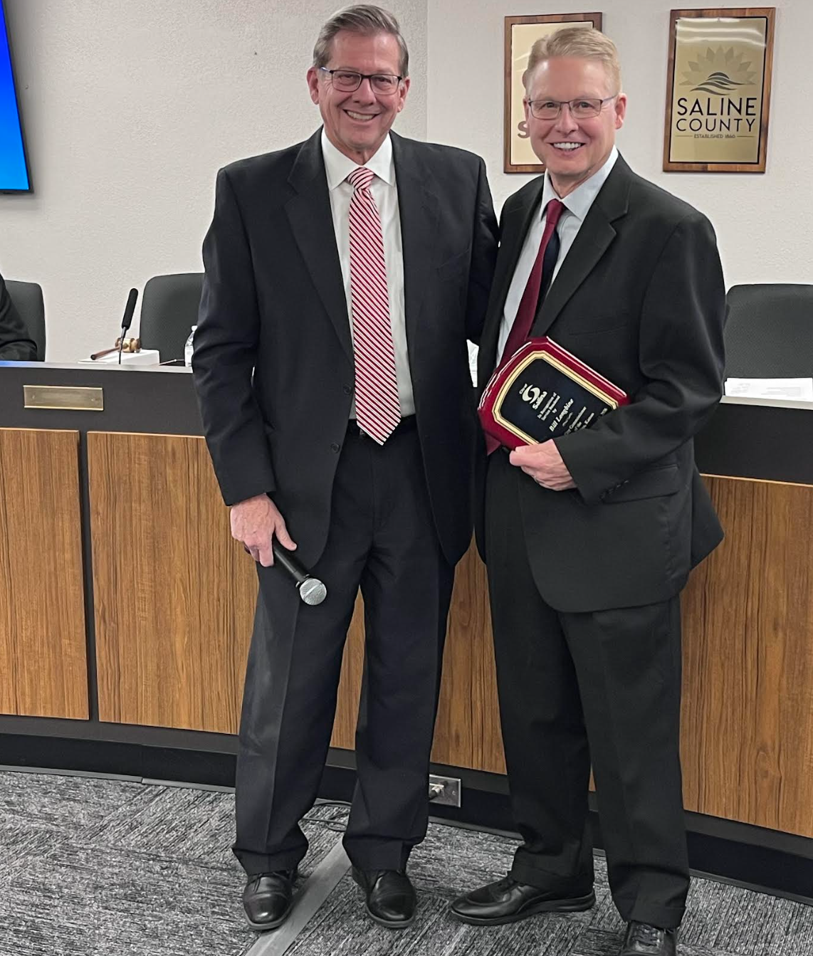 Mayor, Mike Hoppock hands former Commissioner, Bill Longbine a plaque honoring the end of his Commissioner term. Photo by Nicolas Fierro