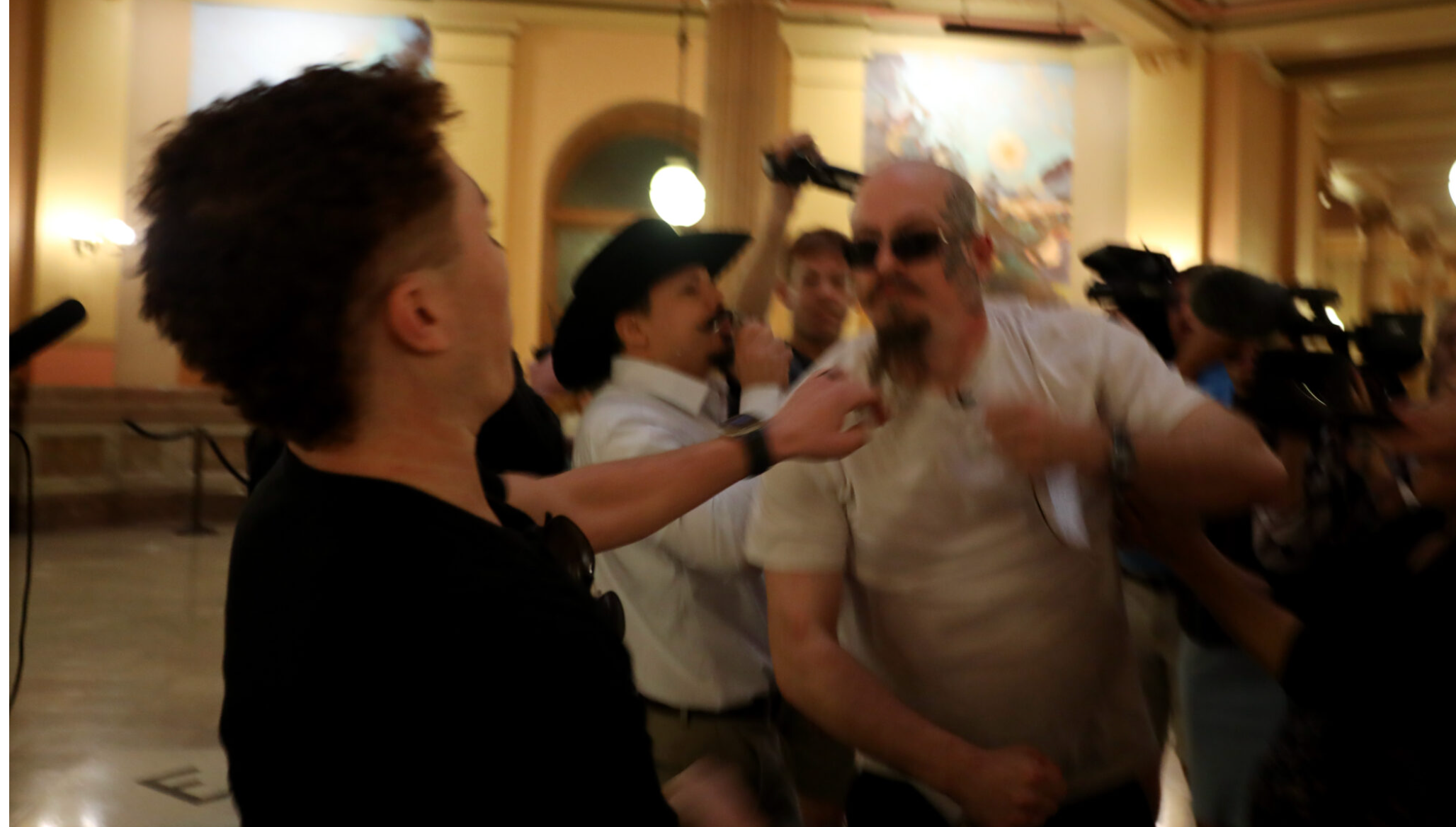  Satanic Grotto president Michael Stewart punches counterprotester Marcus Schroeder after Schroeder attempted to take Stewart’s prayer materials during a March 28, 2025, black mass inside the Kansas Capitol. (Grace Hills/Kansas Reflector)