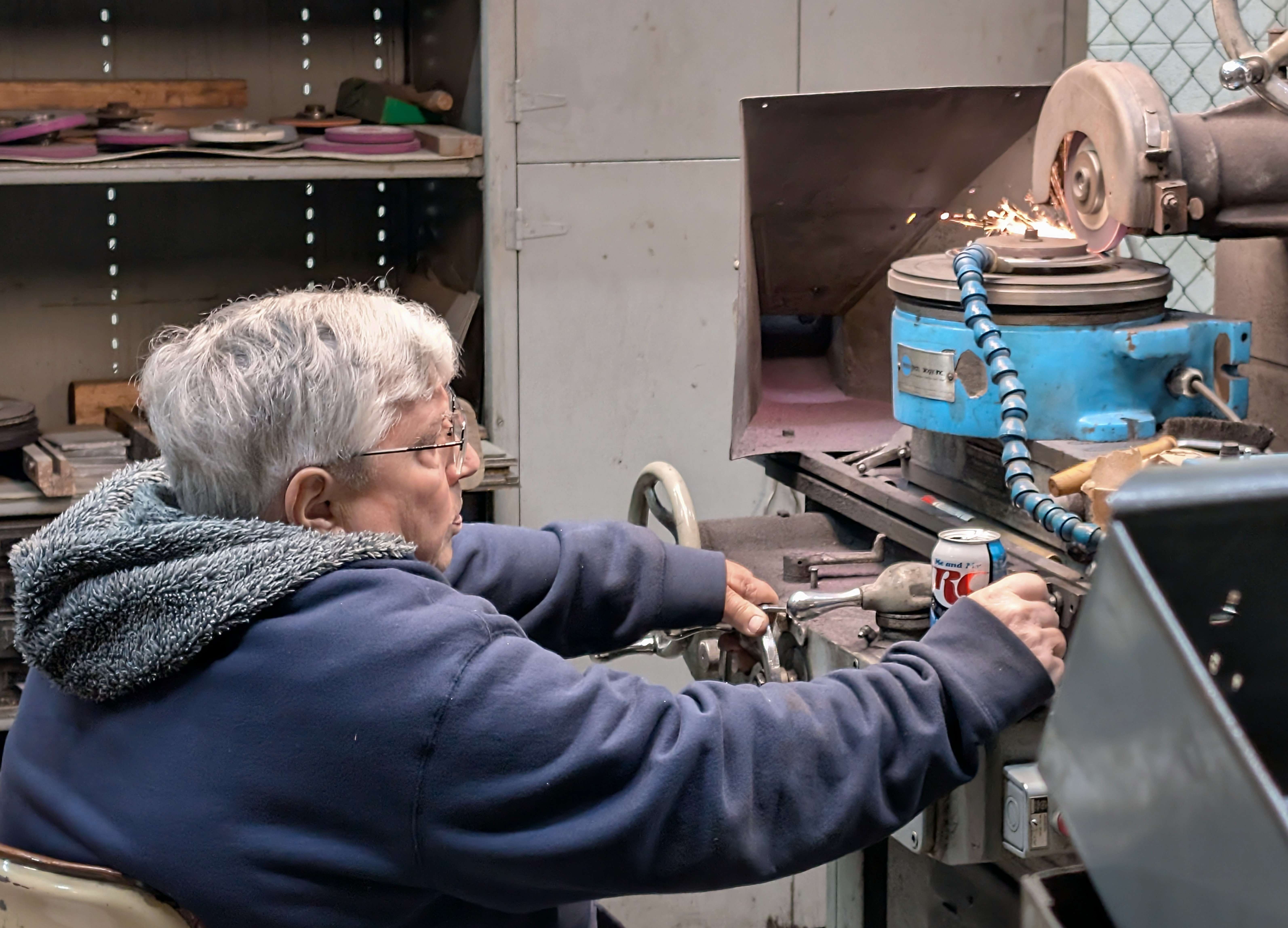 Steve Oberle, a long-time Fuller Industries employee who has served the company in both full- and part-time capacities, demonstrates the meticulous nature of manufacturing work as he manages the manual adjustments of a grinder to finish a brush-cutting blade for a client in the recreational industry.