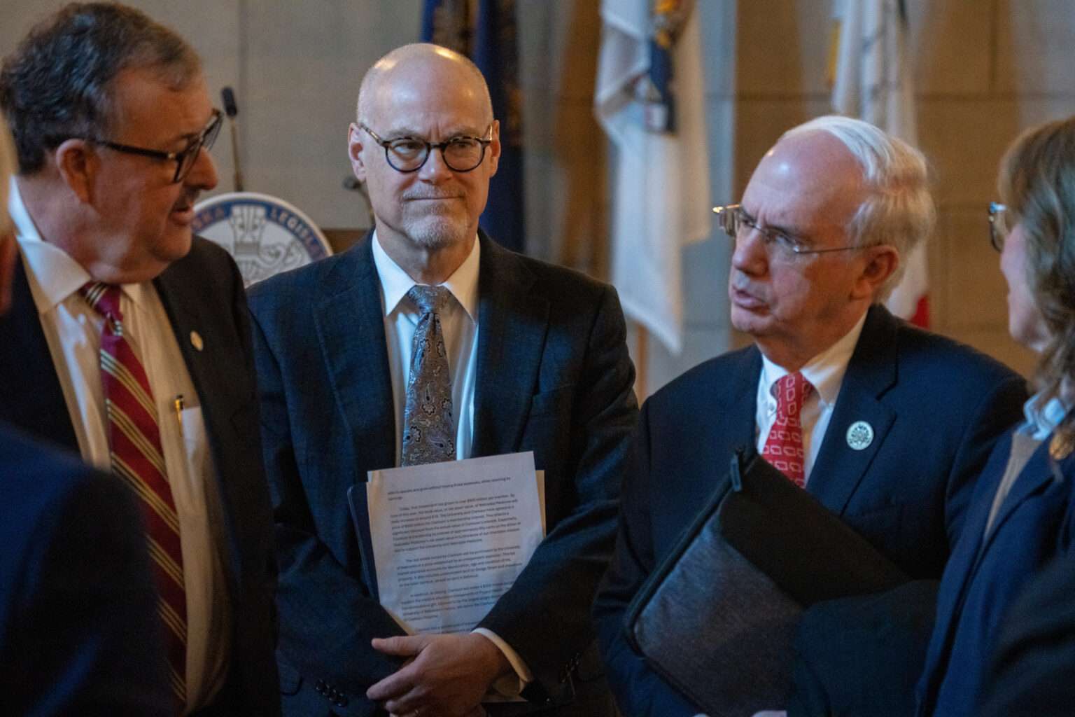 University of Nebraska Dr. Jeffrey Gold, right, speaks with state senators and NU regents after a forum with dozens of Nebraska state senators regarding NU’s proposal to buy out the share of Nebraska Medicine owned by Clarkson Regional Health Services. At center is Dr. Bill Lydiatt, Clarkson’s CEO, and at left is State Sen. Mike Jacobson of North Platte. Jan. 14, 2026. (Zach Wendling/Nebraska Examiner)
