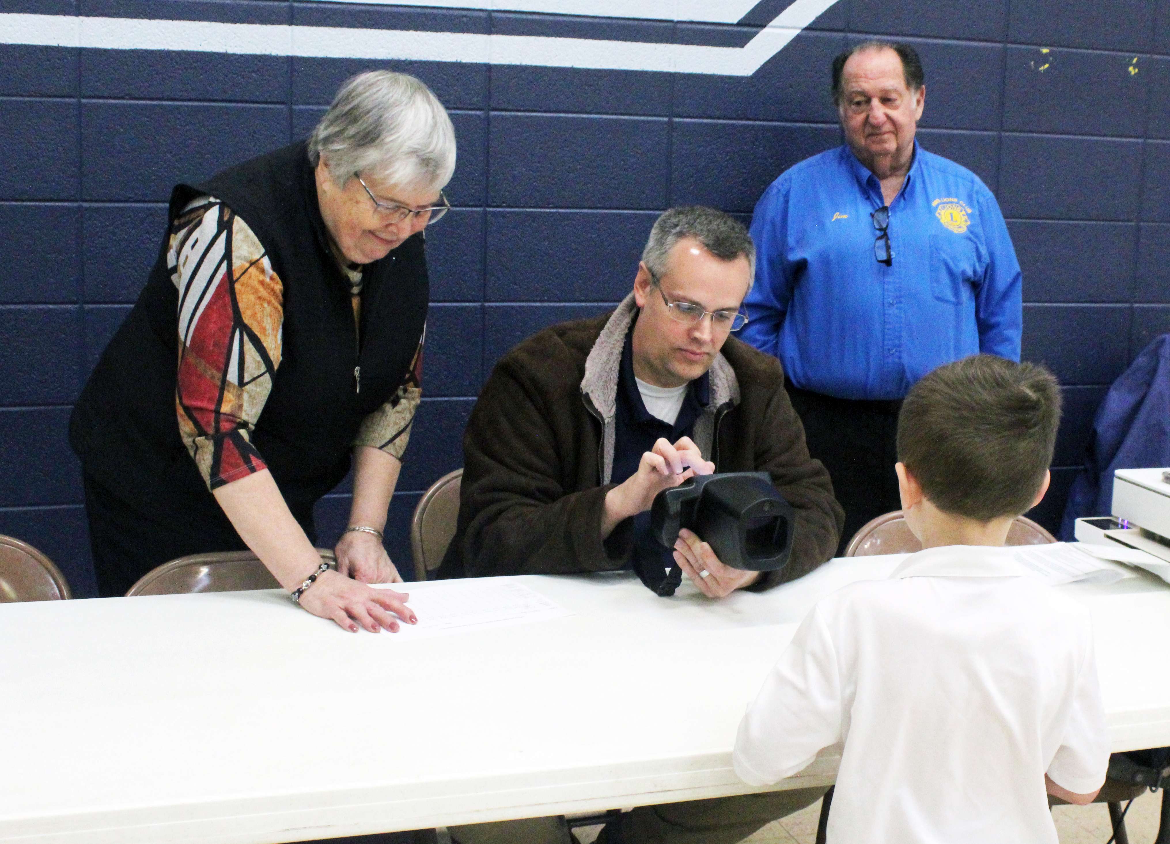Jim Huenergarde, far right, at a recent vision screening at Holy Family Elementary School. Huenergarde, a 29-year Lions member, was recently honored by the organization for his community service and dedication to the club's vision and mission. Photo by Cristina Janney/Hays Post