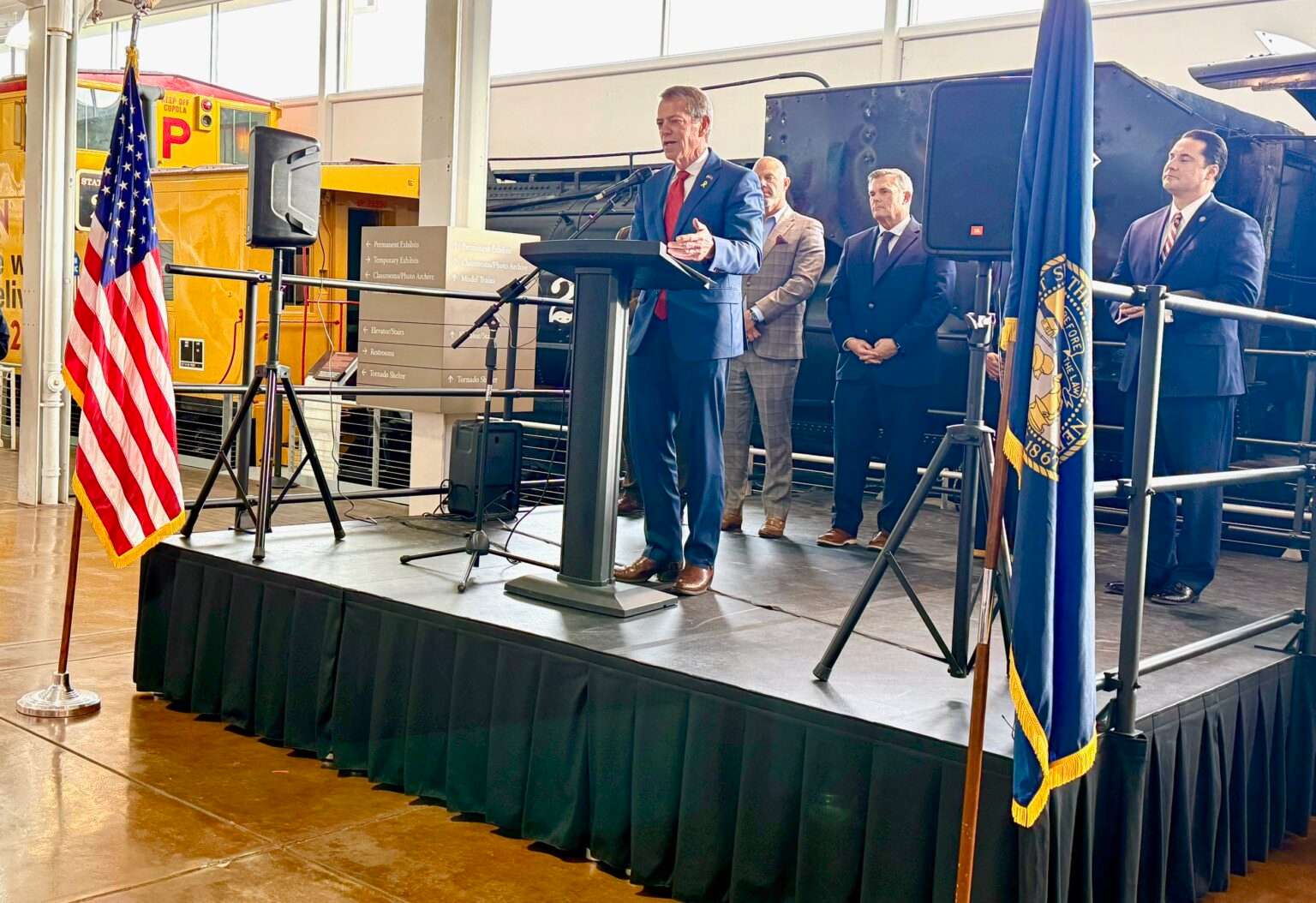 Gov. Jim Pillen speaks at a news conference at the Durham Museum in Omaha, with Union Pacific vintage railroad cars as a backdrop. Those attending included State Sen. Brad von Gillern, chair of the Legislature’s Revenue Committee, who introduced an incentives-focused bill on Pillen’s behalf. Shown on far right is Heath Mello, CEO of the Greater Omaha Chamber of Commerce, and left of von Gillern is Todd Bingham, CEO of Nebraska Chamber of Commerce and Industry. Also speaking was Omaha Mayor John Ewing Jr. (Cindy Gonzalez/Nebraska Examiner)