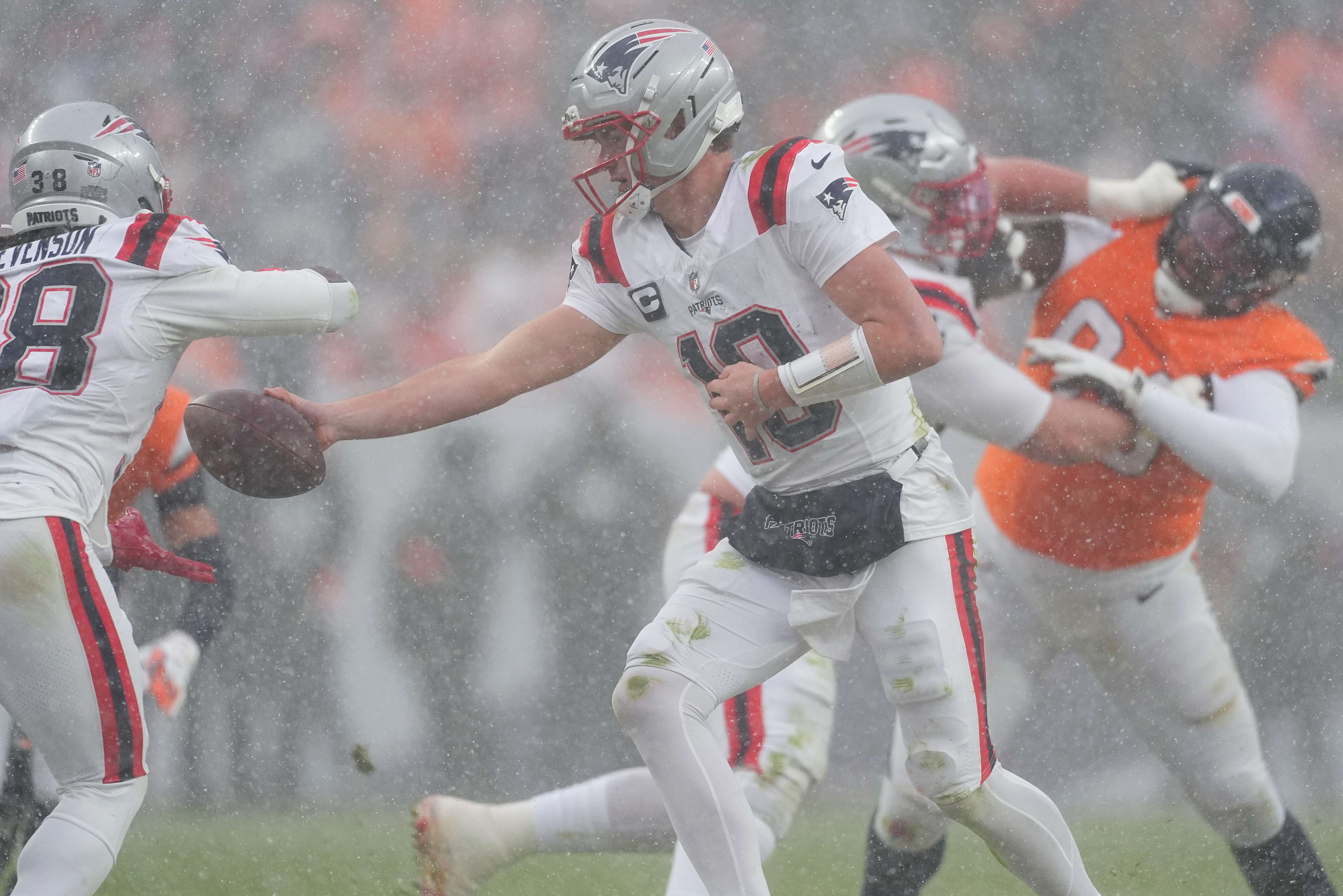 New England Patriots quarterback Drake Maye (10) hands off against the Denver Broncos during the second half of the AFC Championship NFL football game, Sunday, Jan. 25, 2026, in Denver. (AP Photo/David Zalubowski)