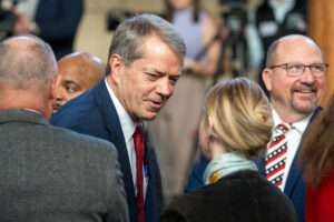 Gov. Jim Pillen, center, greets State Sen. Megan Hunt of Omaha after his annual State of the State address. Jan. 15, 2025. (Zach Wendling/Nebraska Examiner)