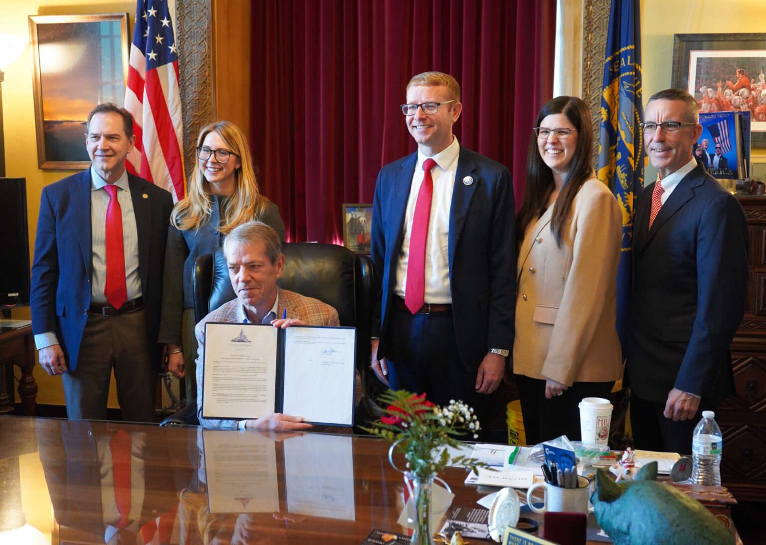 Nebraska Gov. Jim Pillen, seated at center, holds up a newly signed executive order barring state health officials from diverting federal survivor benefits for youths in foster care to cover the costs of their care. Behind the governor are, from left, State Sen. Brian Hardin of Gering, chair of the Legislature’s Health and Human Services Committee; U.S. Deputy Assistant HHS Secretary Martha Verno in the Administration for Children and Families; U.S. Assistant HHS Secretary Alex Adams, head of the federal department’s Administration for Children and Families; Dr. Alyssa Bish, director of the DHHS Division of Children and Family Services; and Nebraska DHHS CEO Steve Corsi, at right. Jan. 27, 2026. (Courtesy of Nebraska Department of Health and Human Services)
