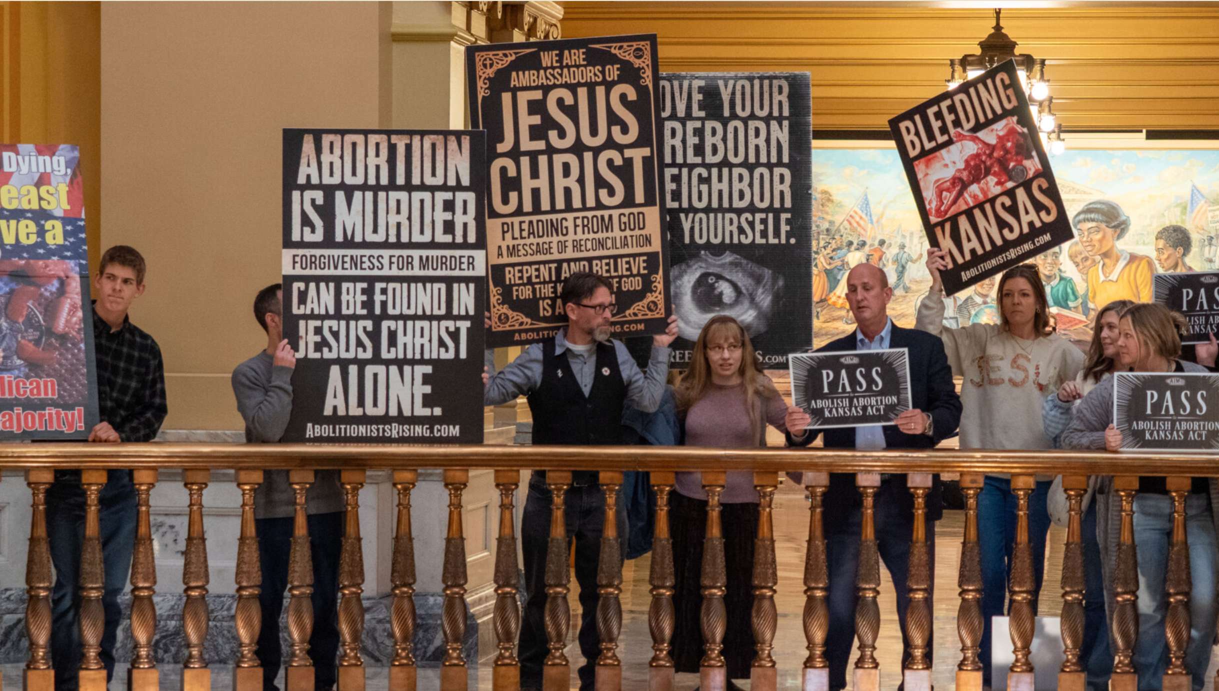 Clifton Boje, center in vest and holding the “Jesus Christ” sign on his shoulders, leads a rally Jan. 27, 2026, in the Capitol rotunda with allies in the Abortion is Murder organization. AIM wants the Kansas Legislature to pass a bill declaring abortion the equivalent of murder statewide. (Photo by Sherman Smith/Kansas Reflector)