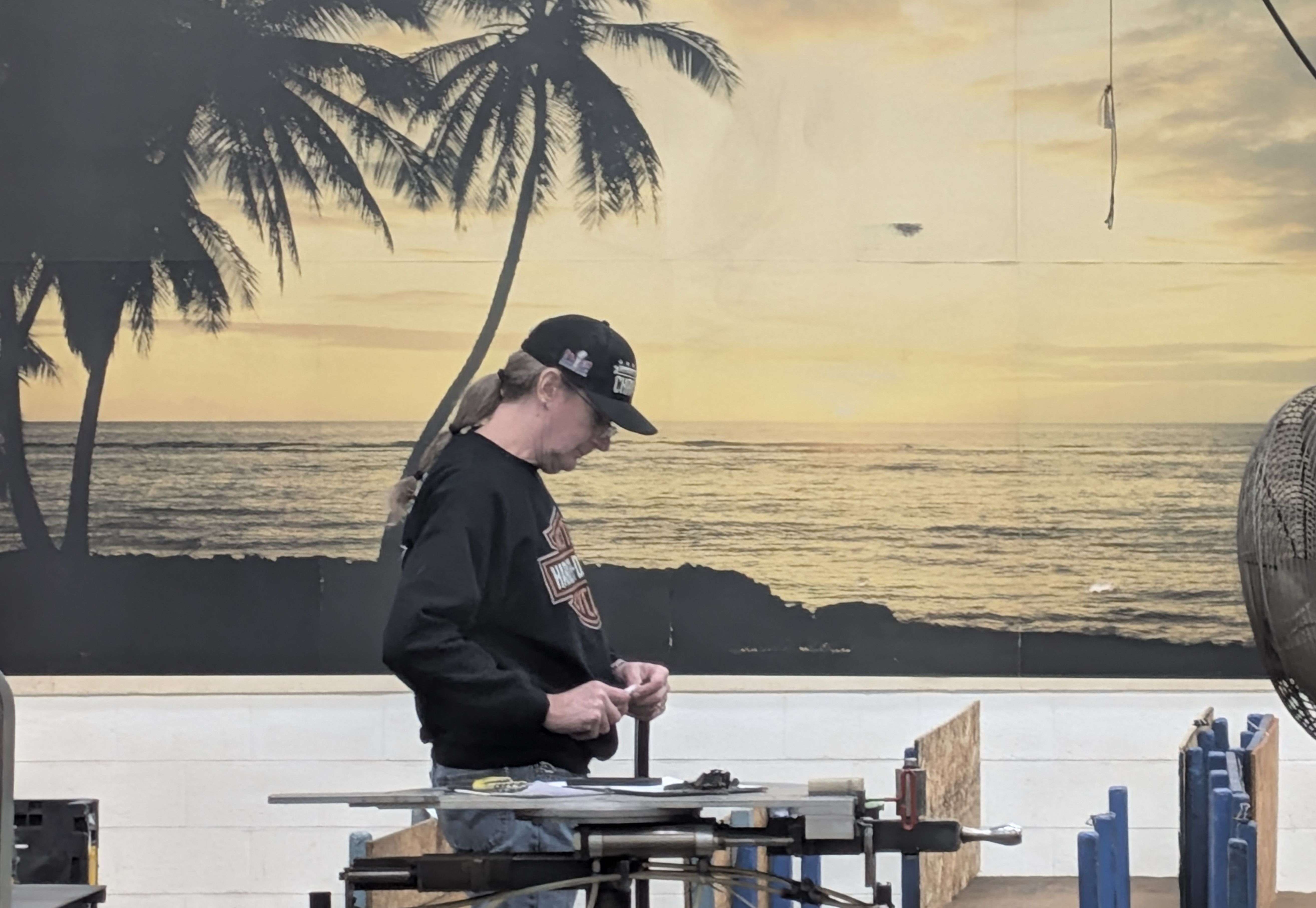 No, Fuller Industries employee Leo Sobba is not on a South Pacific beach. He is just working in front one of the 15 photographic murals that have decorated the factory walls for over 30 years.