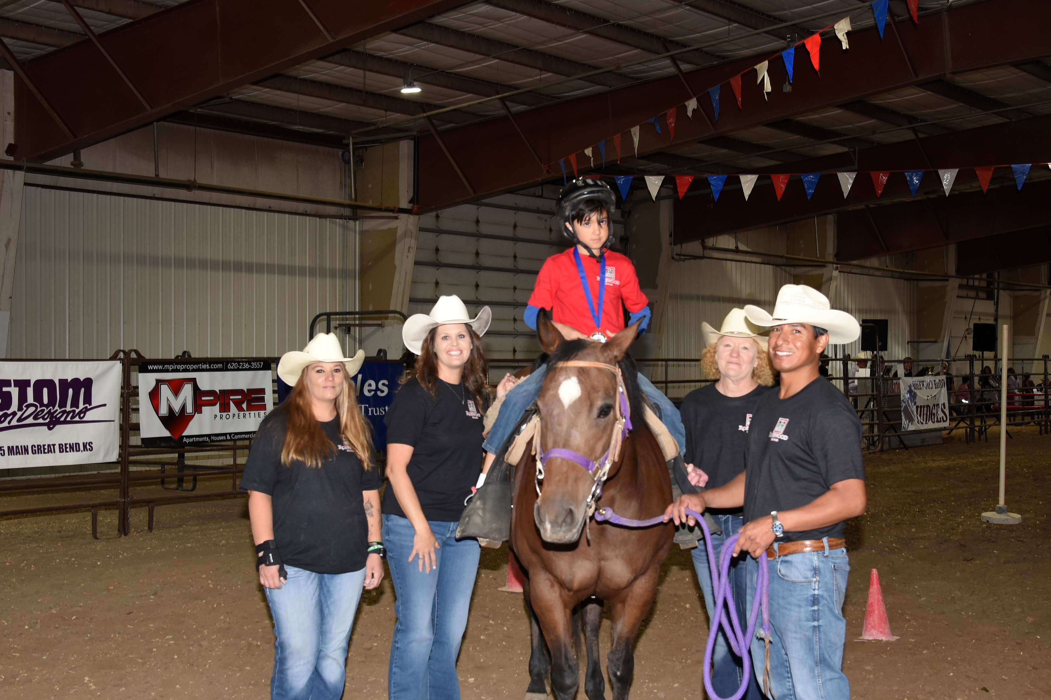 Karl Rose sits poised atop his horse, “Harriet” following his Trail Pattern ride at Rosewood Rodeo, held at Barton County Fair Grounds Expo III Arena on Oct. 3. This was Karl’s rodeo debut, along with two other youth riders. “Our youth riders didn’t know what to expect,” said Rosewood Ranch Manger Eric Hammond, “but they had a great time. It was a special day for them, for sure.” Karl is pictured left to right with Rosewood Rodeo horse handlers Tandy Webb, April Robinson (Director of Rosewood Case Management), Melinda Hosfelt and Juan Bodine