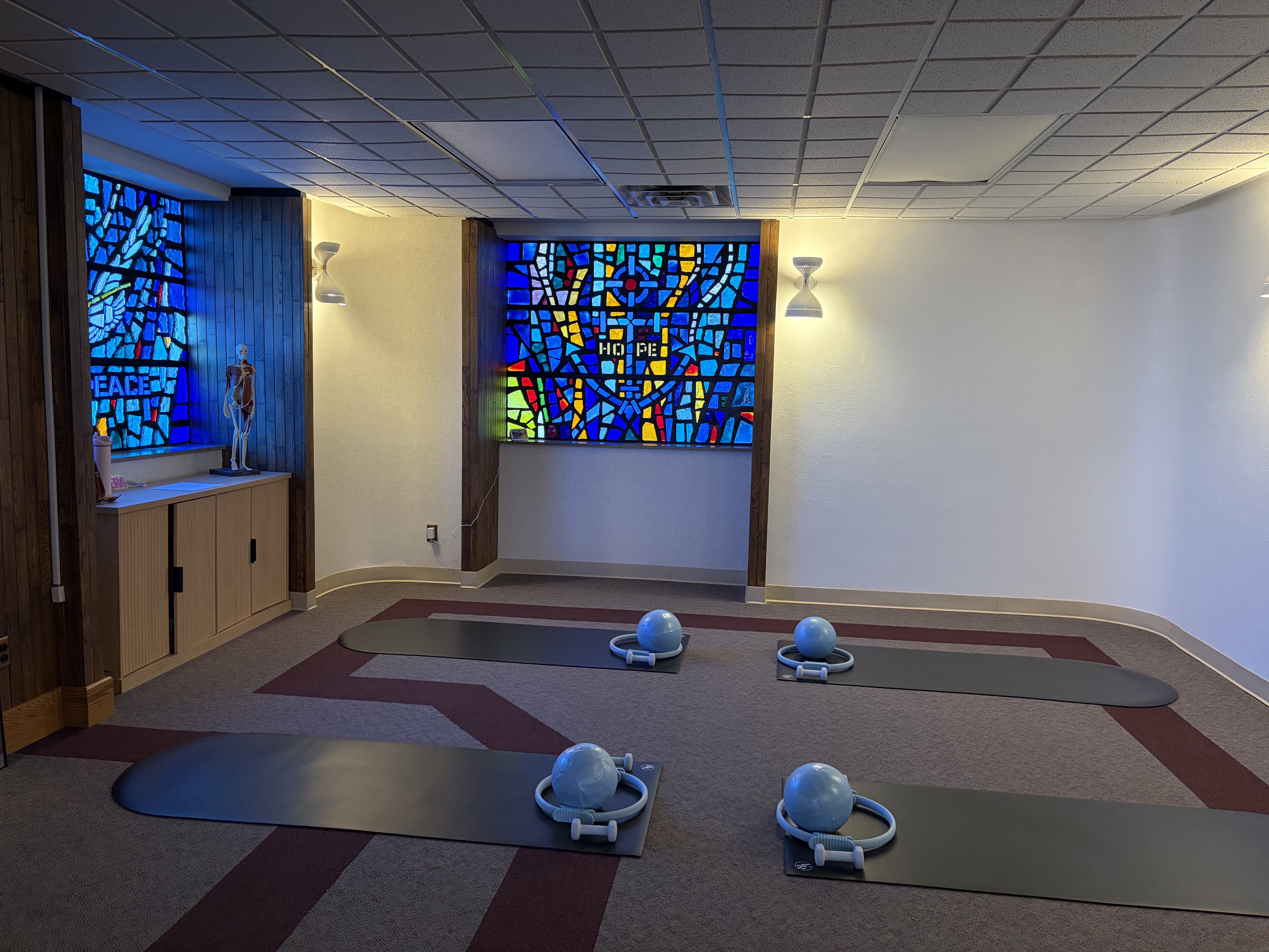 Four Pilate mats located inside PS Studios by Isabelle, with the two stained-glass windows detailing the words "Peace" and "Hope." Photo by Alin Hett/Hays Post