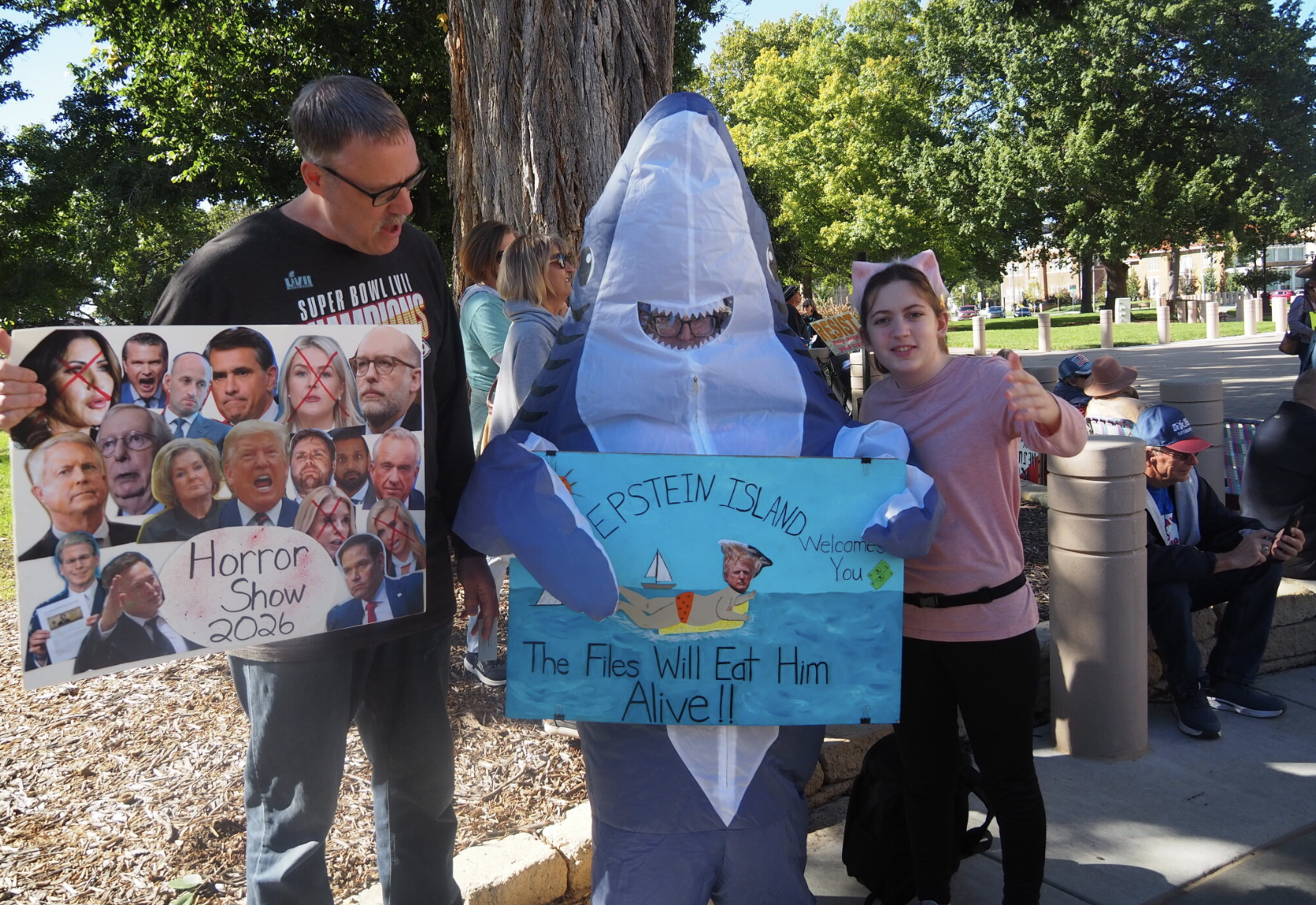 The family of Kevin, Michelle and Harlan Manning offers a colorful take on politics Oct. 17, 2026, outside the Kansas Capitol during a rally to spur voter participation in the Nov. 3 midterm election. The event offered them an opportunity to share personal perspectives on government, especially leadership of President Donald Trump. (Photo by Tim Carpenter/Kansas Reflector)