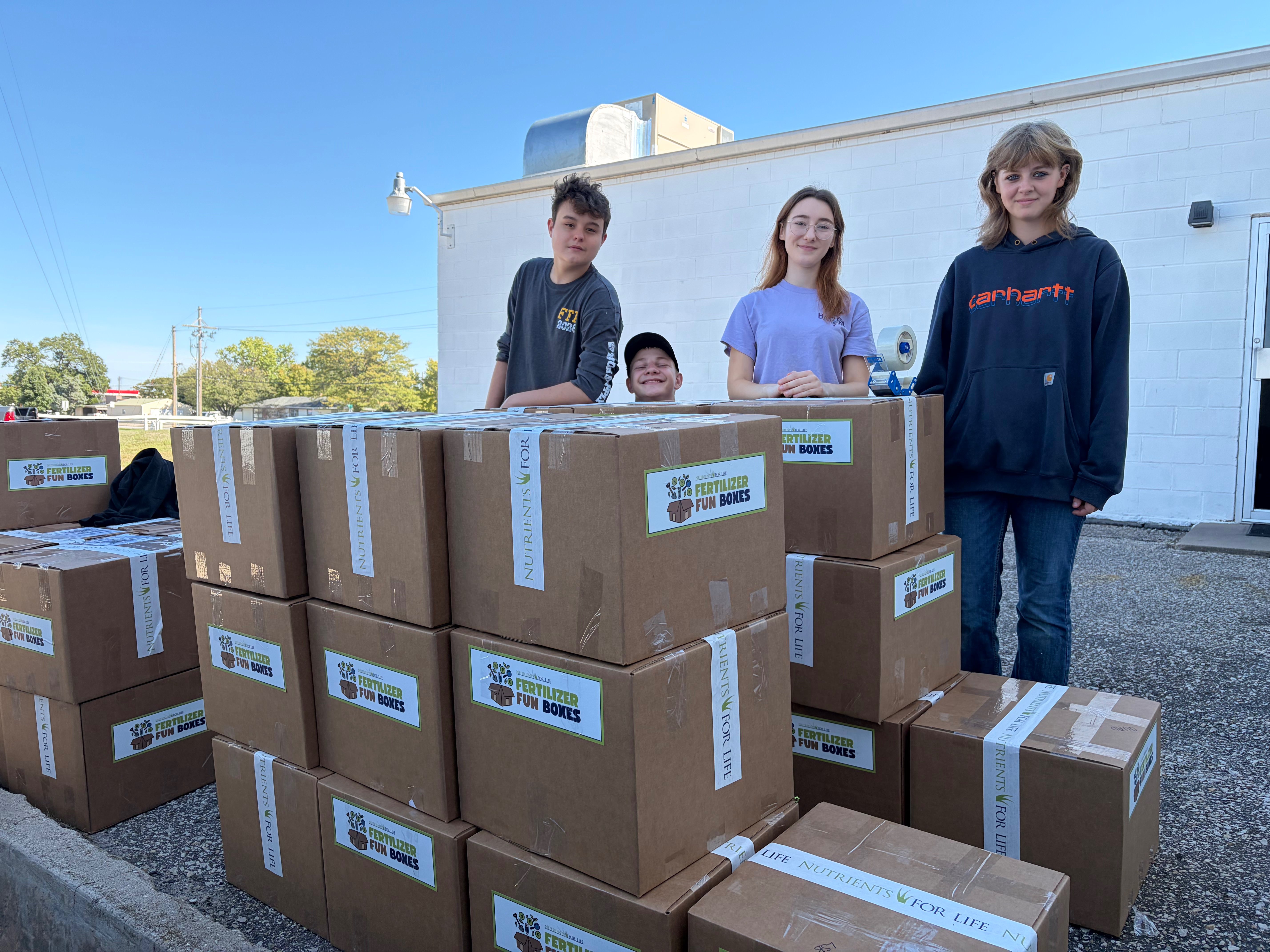 Hays High FFA students stand behind Fertilizer Fun boxes ready to be shipped out. From left: Tucker Farthing, Marshall Olson, Jennifer Sewell and Maggie Olson. Photo by Alin Hett/Hays Post